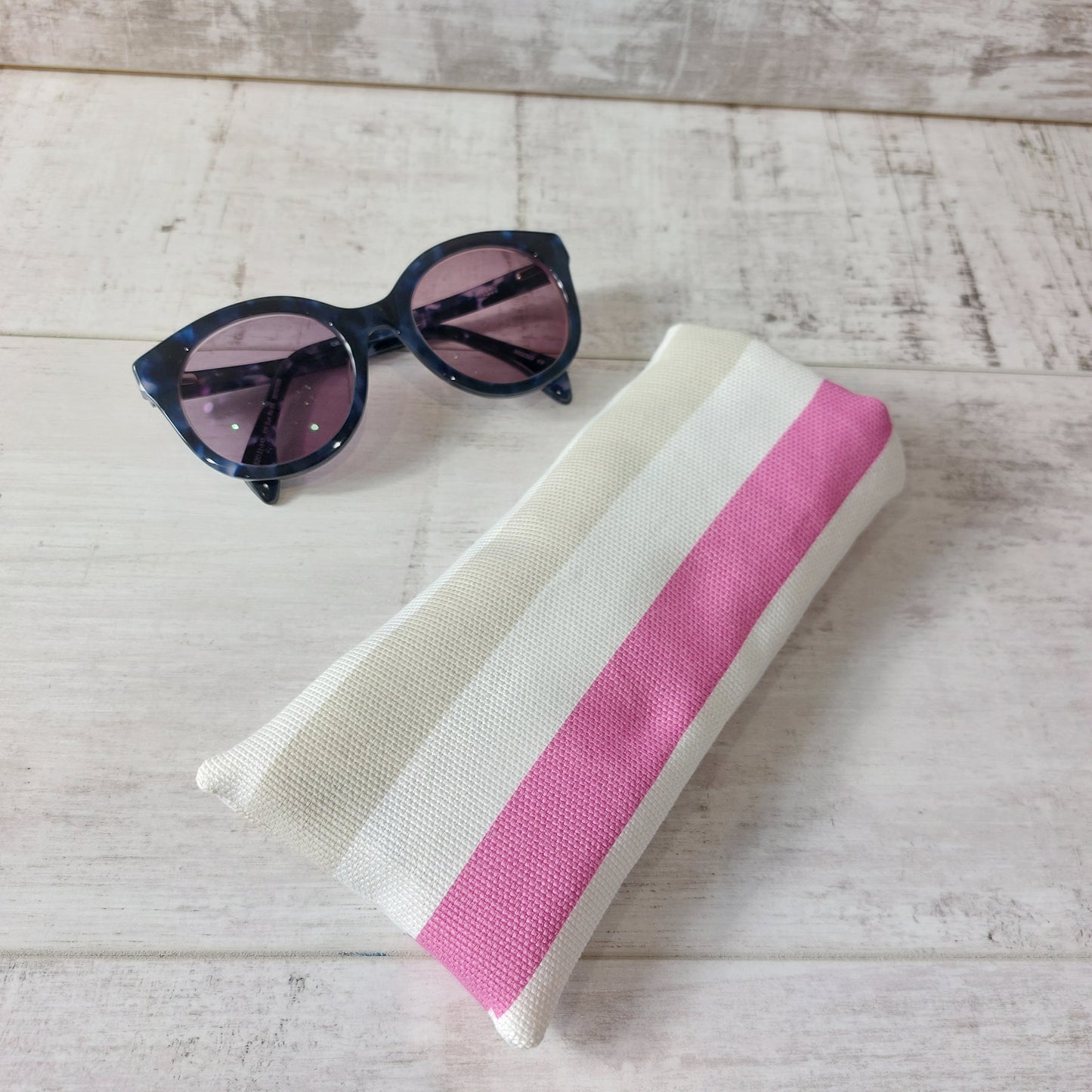 Pink marine stripe sunglasses case with sunglasses.