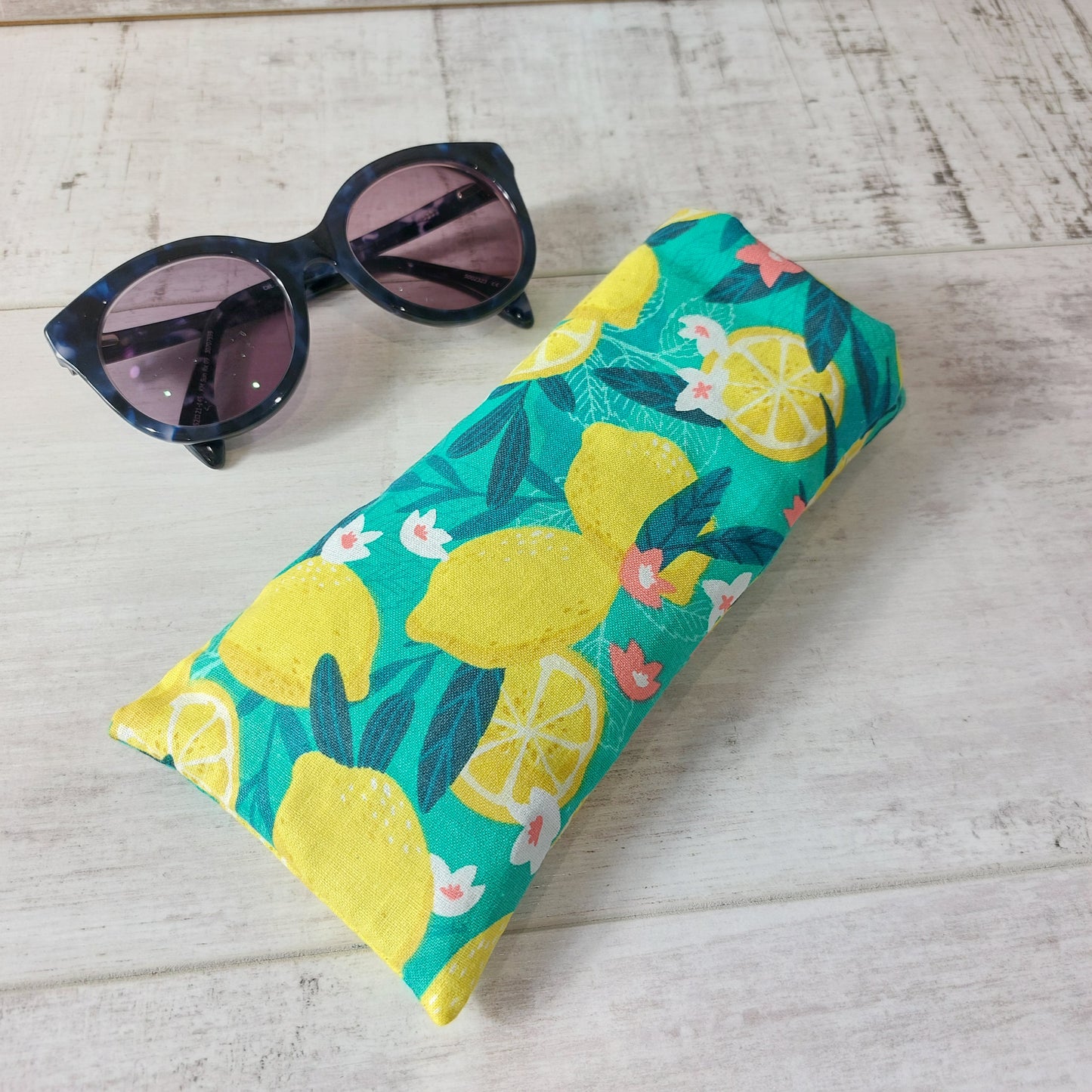 Bold green and yellow Sicilian lemon print glasses case, pictured with sunglasses.