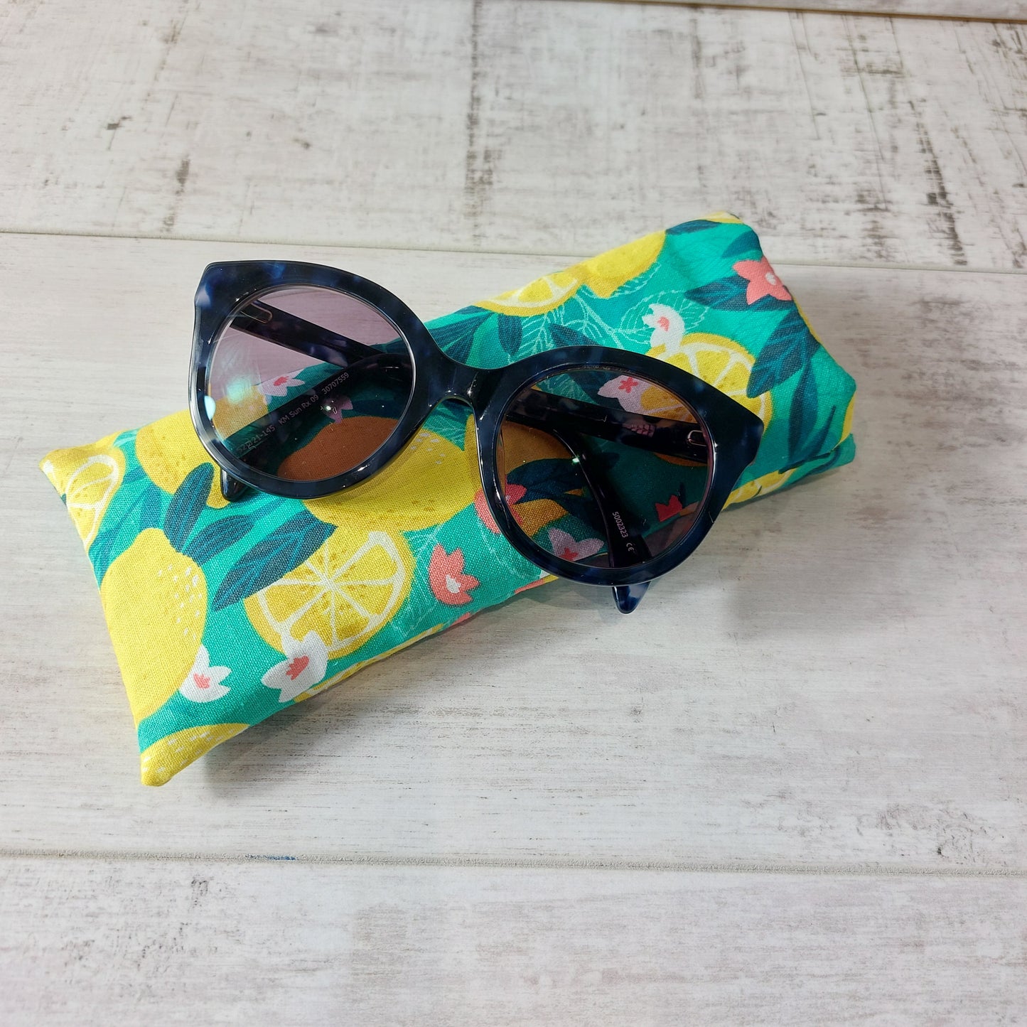 Bold green and yellow Sicilian lemon print glasses case, with sunglasses resting on top.