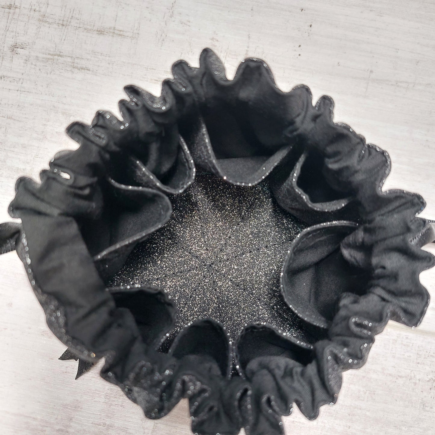 Black glitter jewellery pouch, top view, with black glitter lining and eight inner pockets.