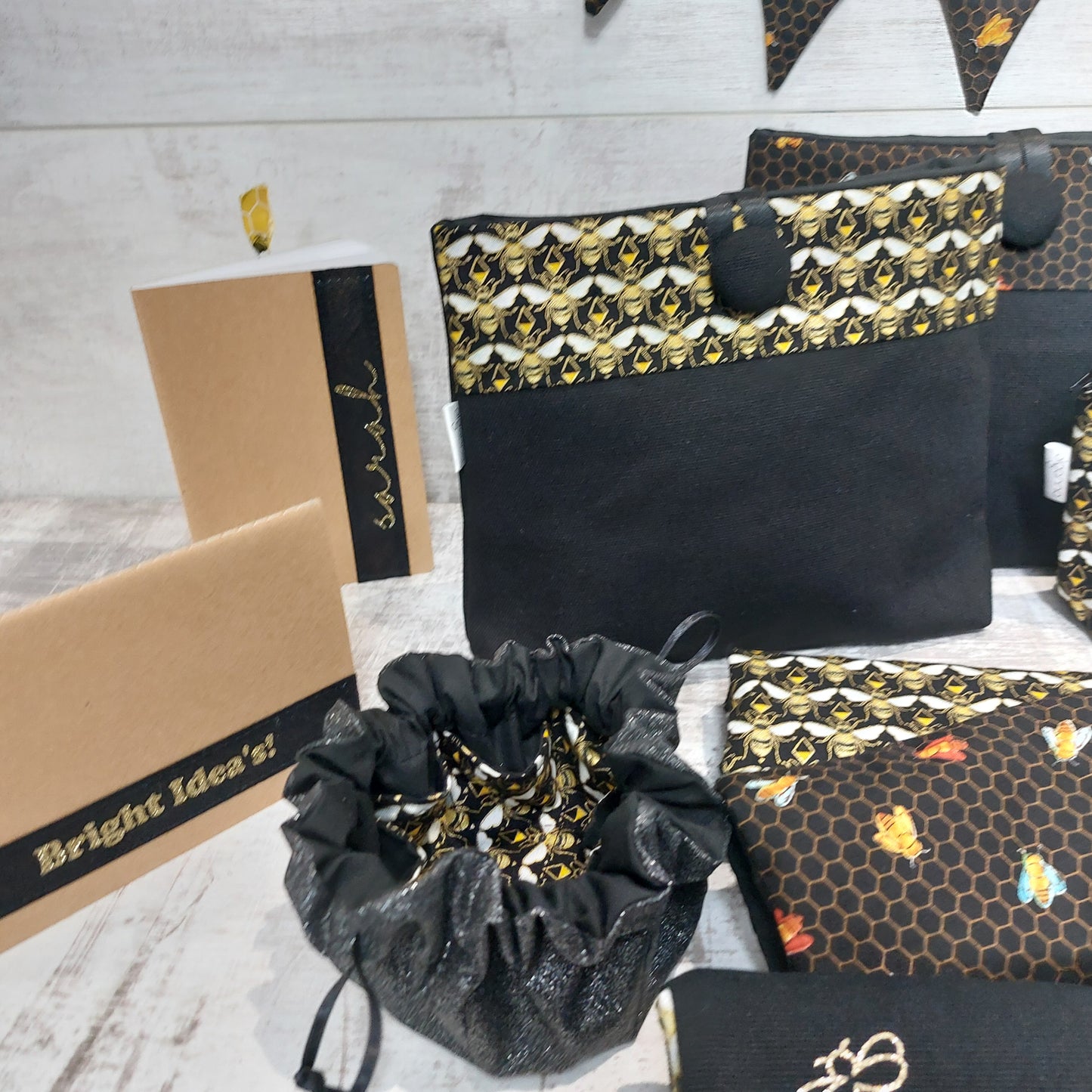 Jewellery pouch in black and gold, with bee print interior, pictured with coordinated accessories of button pouches, glasses cases and notepads.