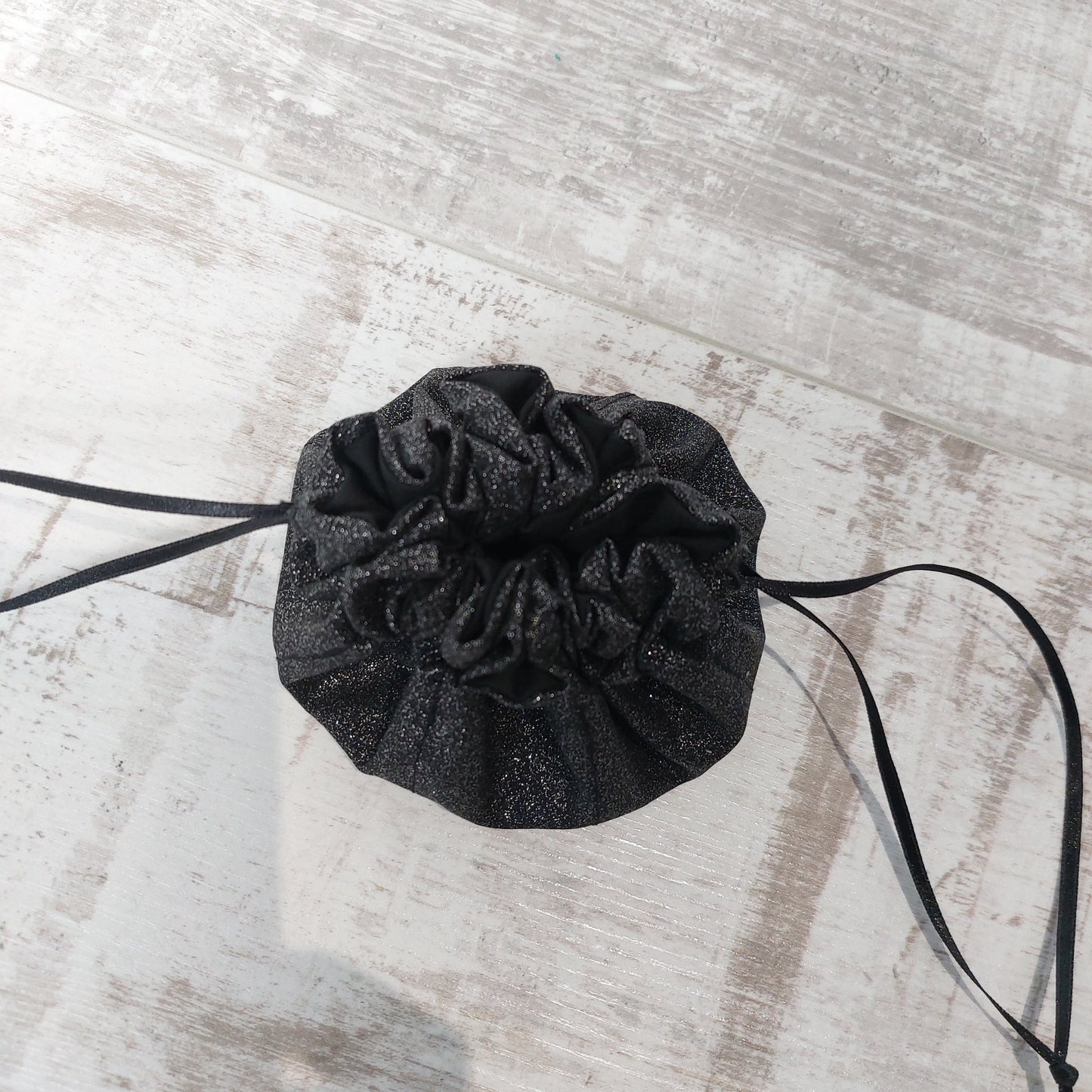 Black glitter jewellery pouch, closed with ribbon pull-tie.