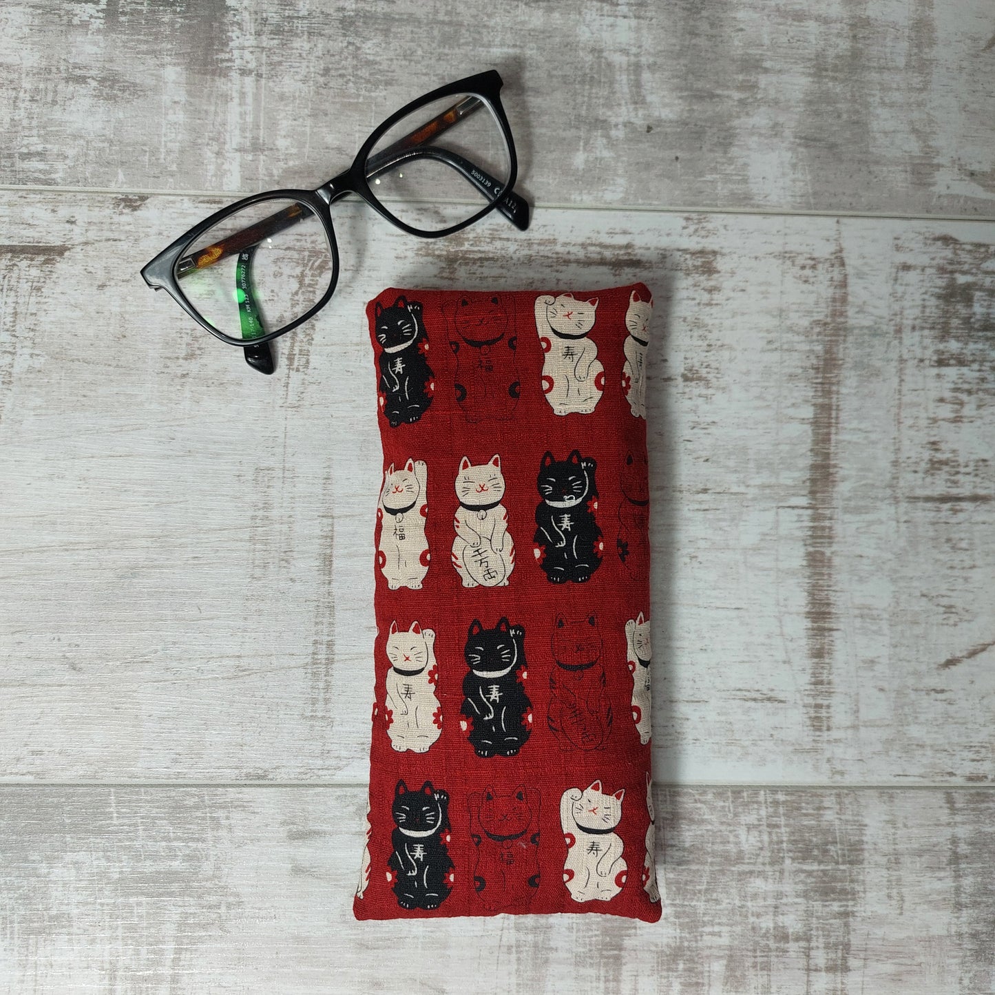 Red lucky cat Maneki Neko glasses case by Olganna, pictured with glasses.