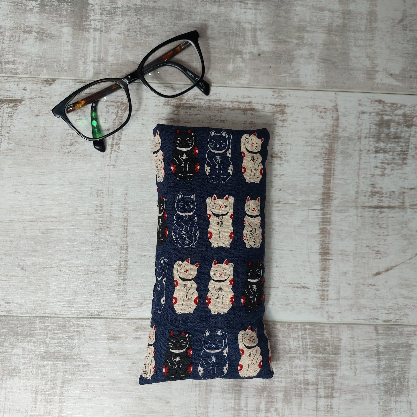 Cute kawaii print black lucky cat glasses case by Olganna, pictured with glasses.