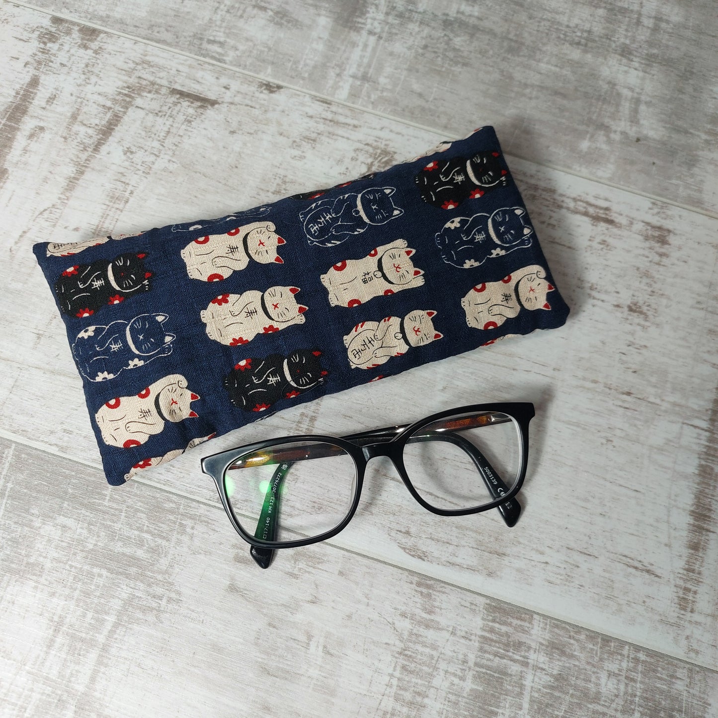 Navy lucky cat Maneki Neko glasses case, pictured with glasses.