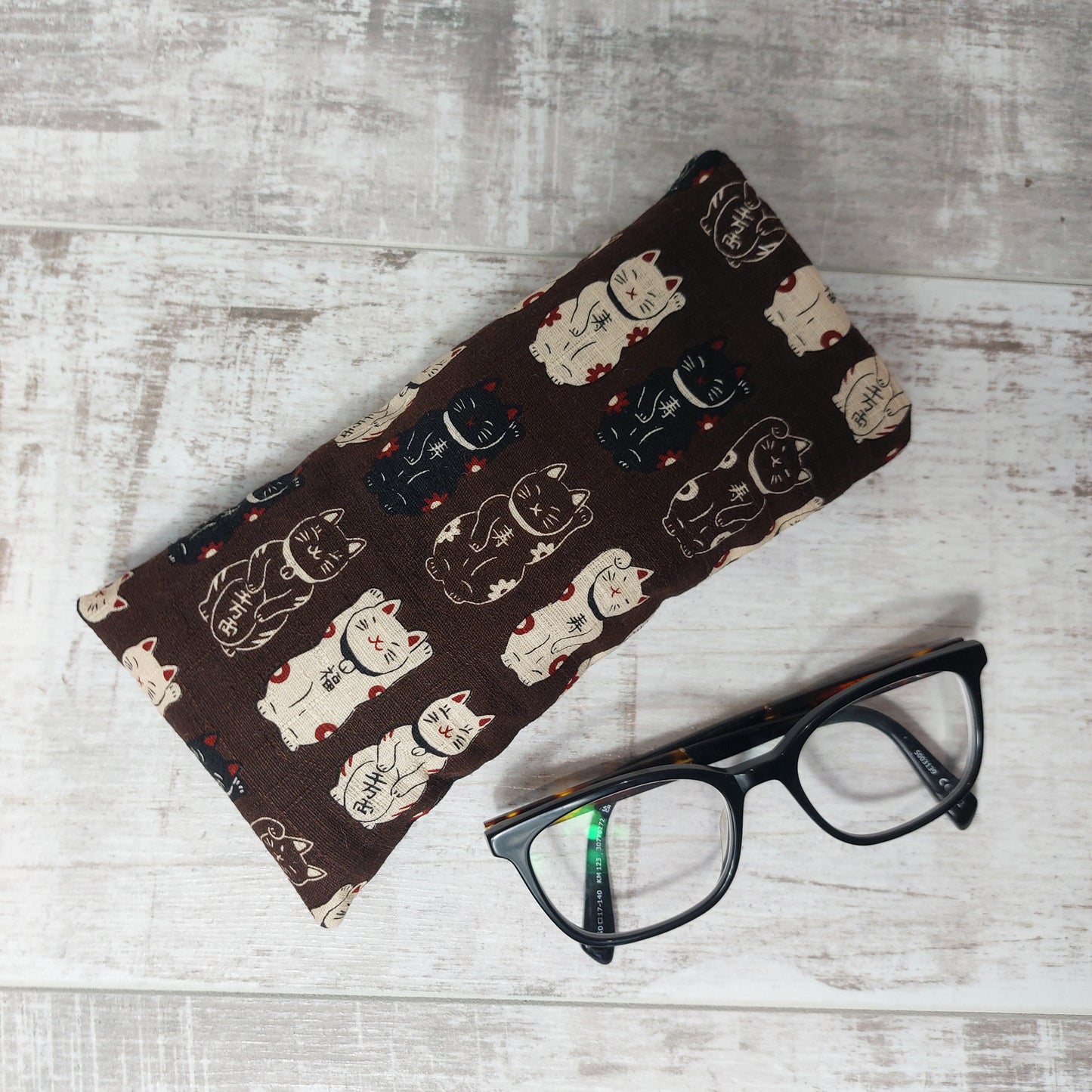 Chocolate brown lucky cat Maneki Neko glasses case by Olganna, pictured with glasses.