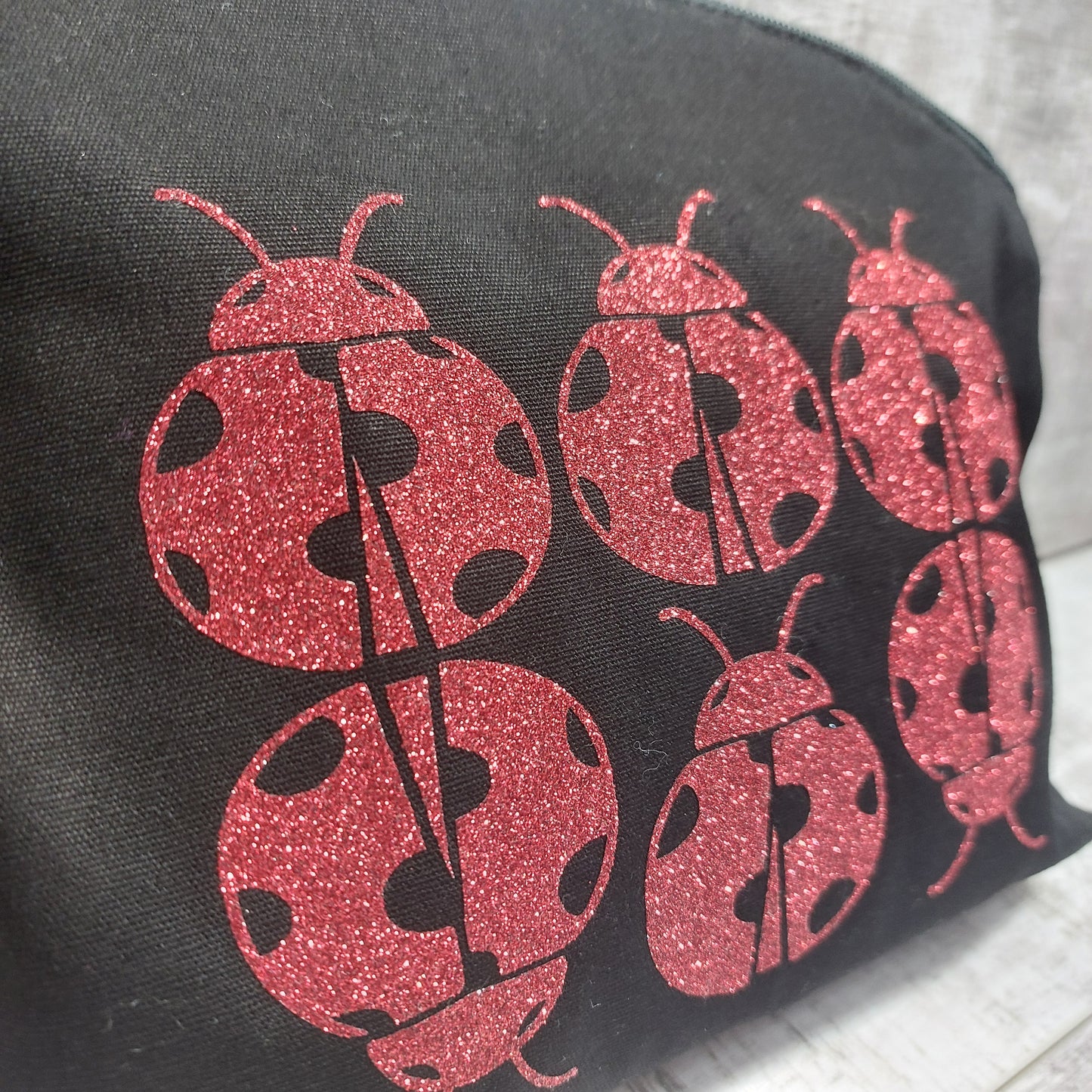 Close up of black makeup bag with glittery red ladybird print.