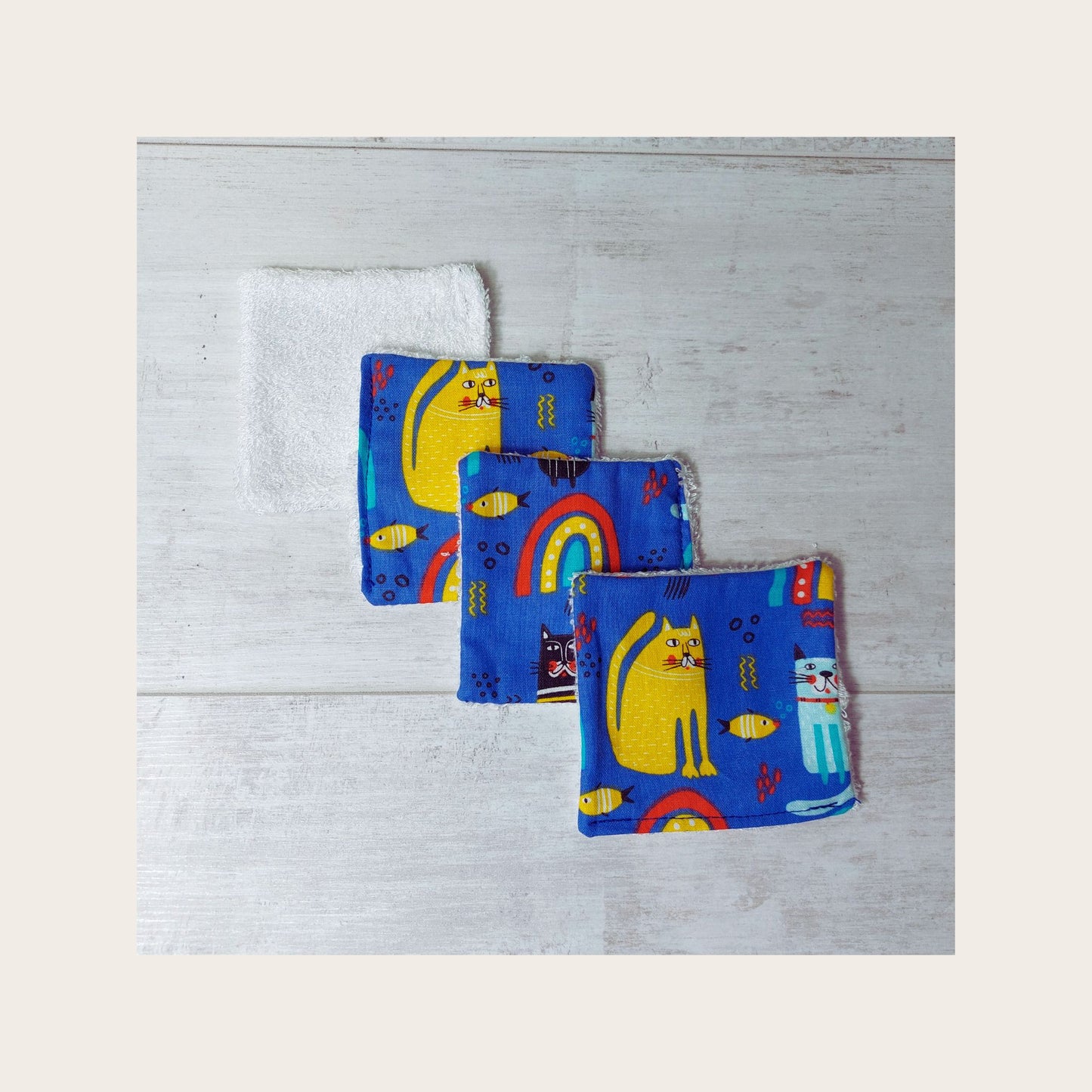 Four vibrant blue rainbow cat print reusable bamboo face wipes by Olganna.