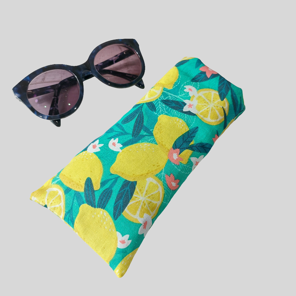 Bold green and yellow Sicilian lemon print glasses case, pictured with sunglasses.