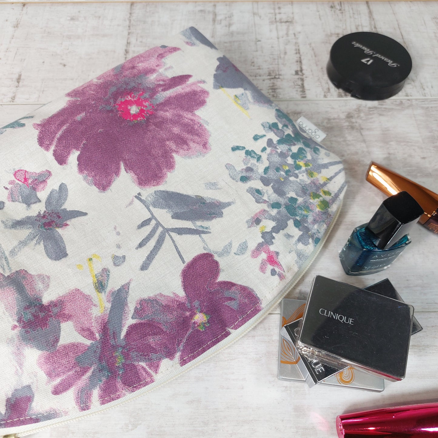 Floral makeup bag in pastel shades pictured with beauty essentials.