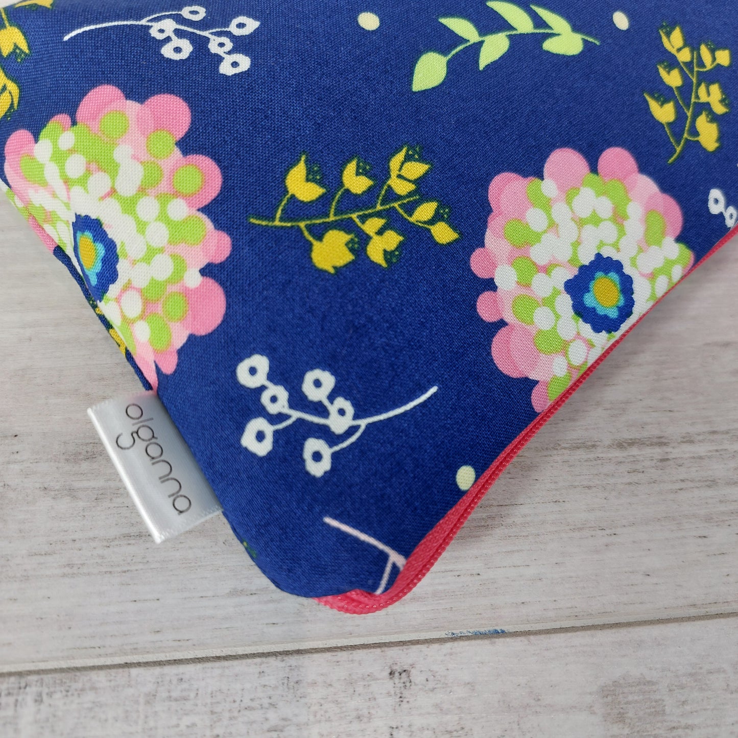 Close-up view of royal blue Spring floral print makeup bag with side label saying 'olganna'.
