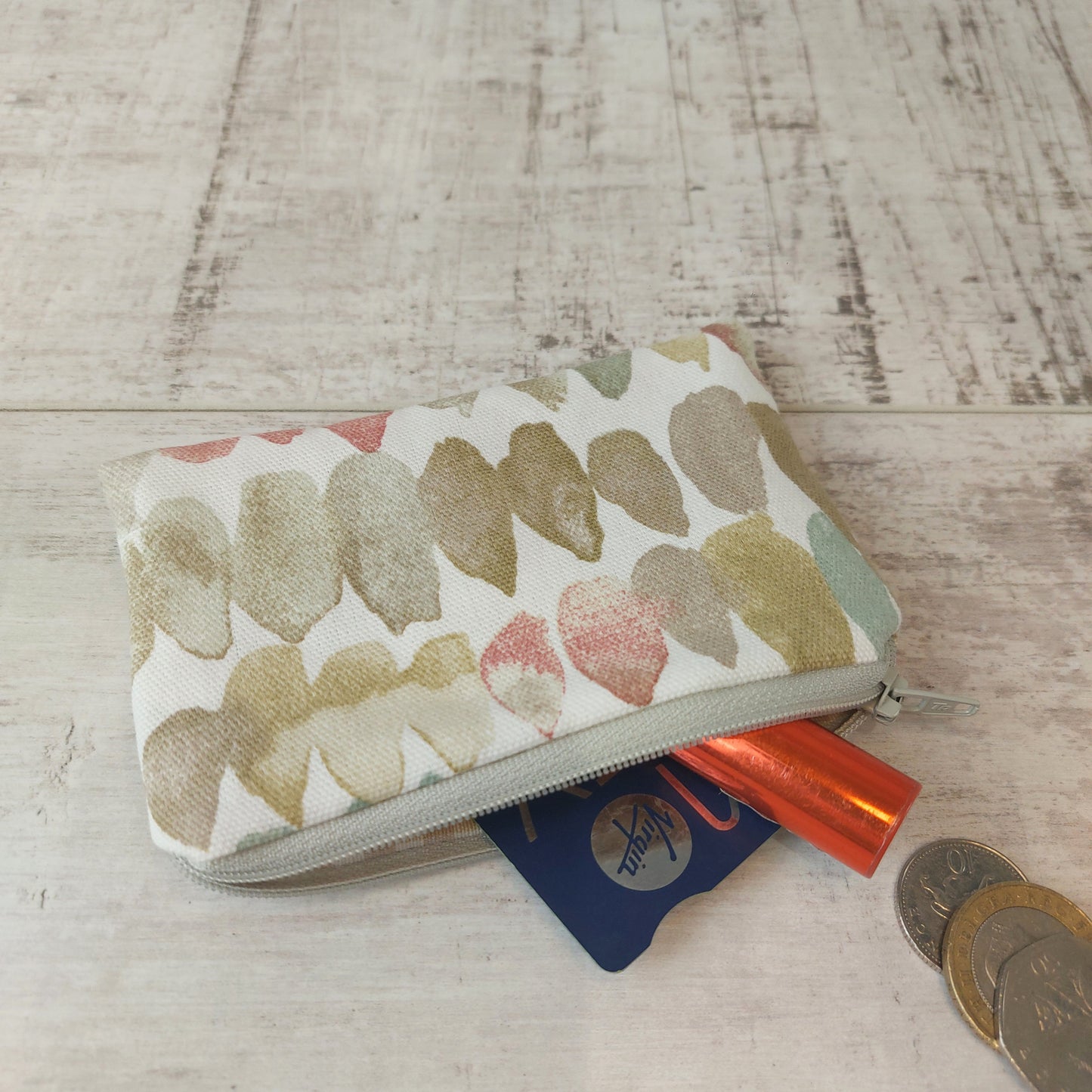 Neutral stone pebble print small zip pouch pictured with coins, card and lipstick.
