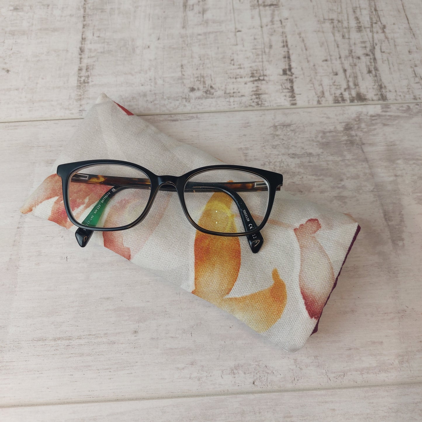 Autumn Leaves padded glasses case with glasses on top.