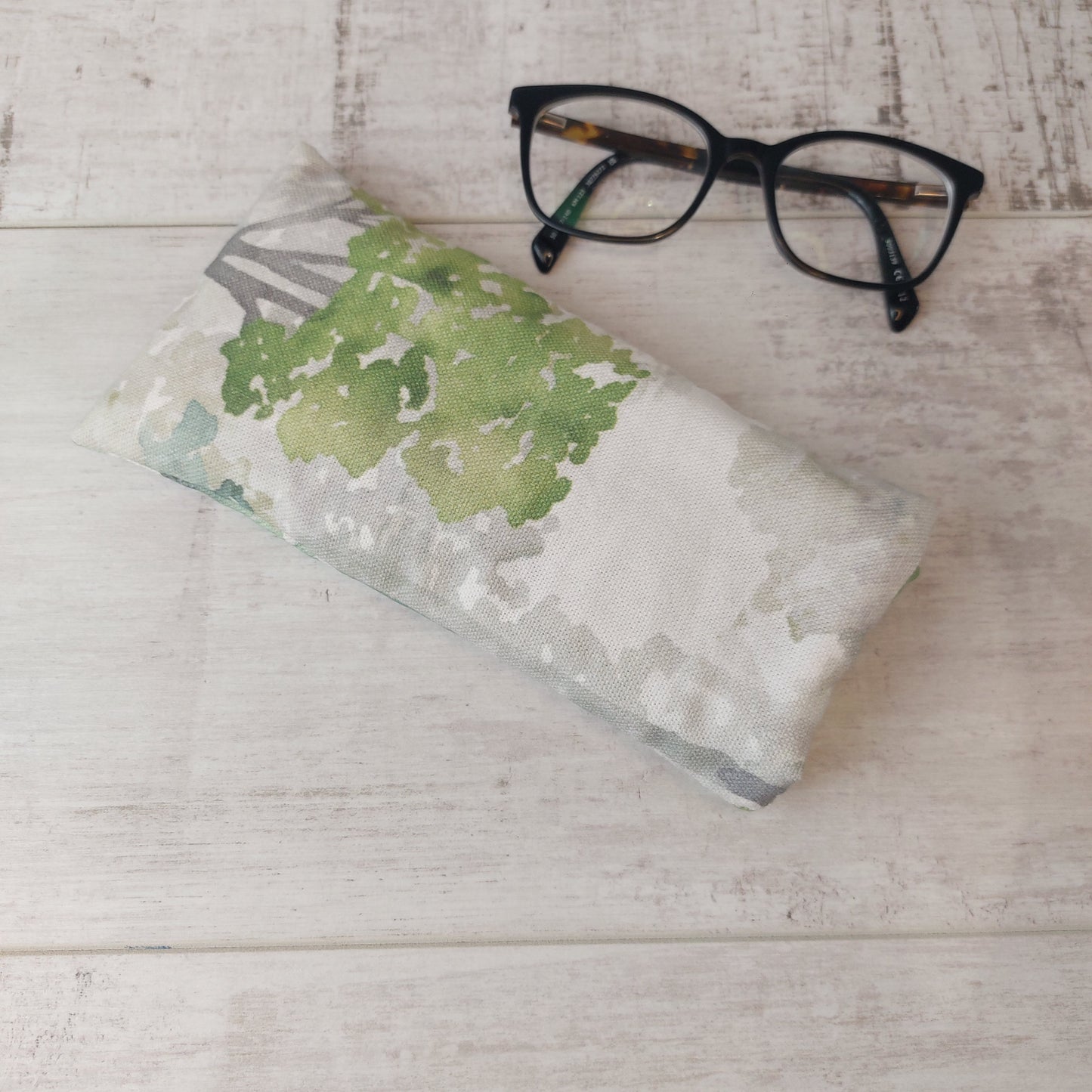 Green watercolour tree print padded glasses case by Olganna, pictured with glasses.