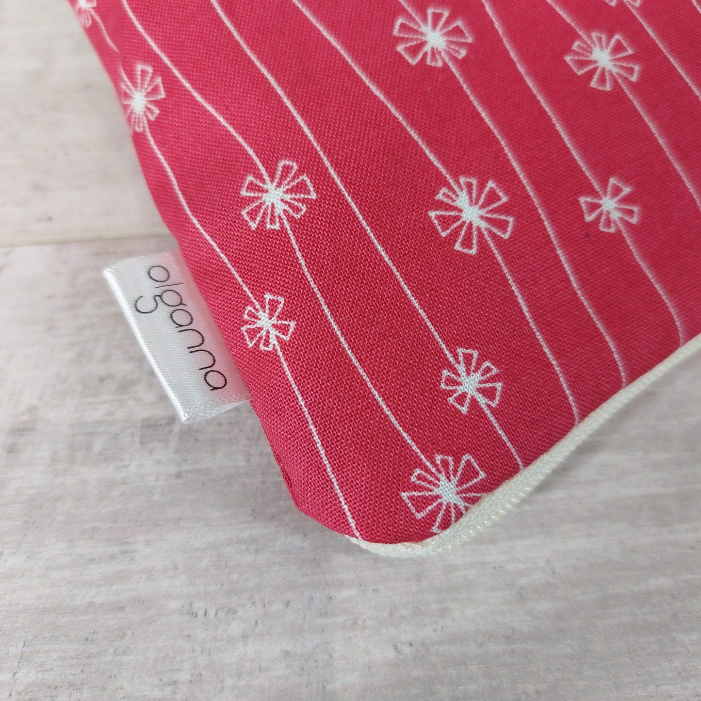 Close-up view of red and white flower print makeup bag with side label saying 'olganna'.