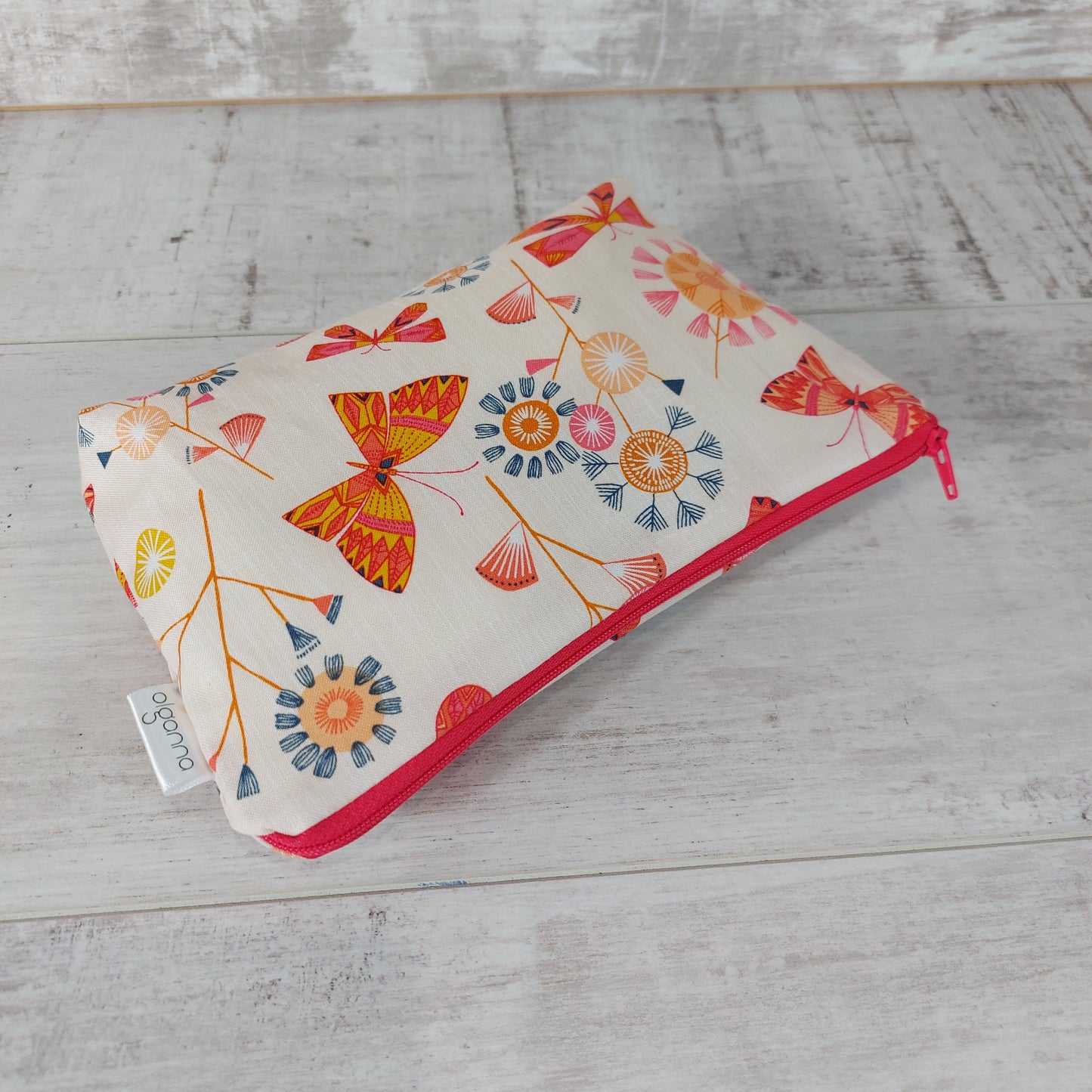 Spring floral and butterfly print makeup bag, lying down.