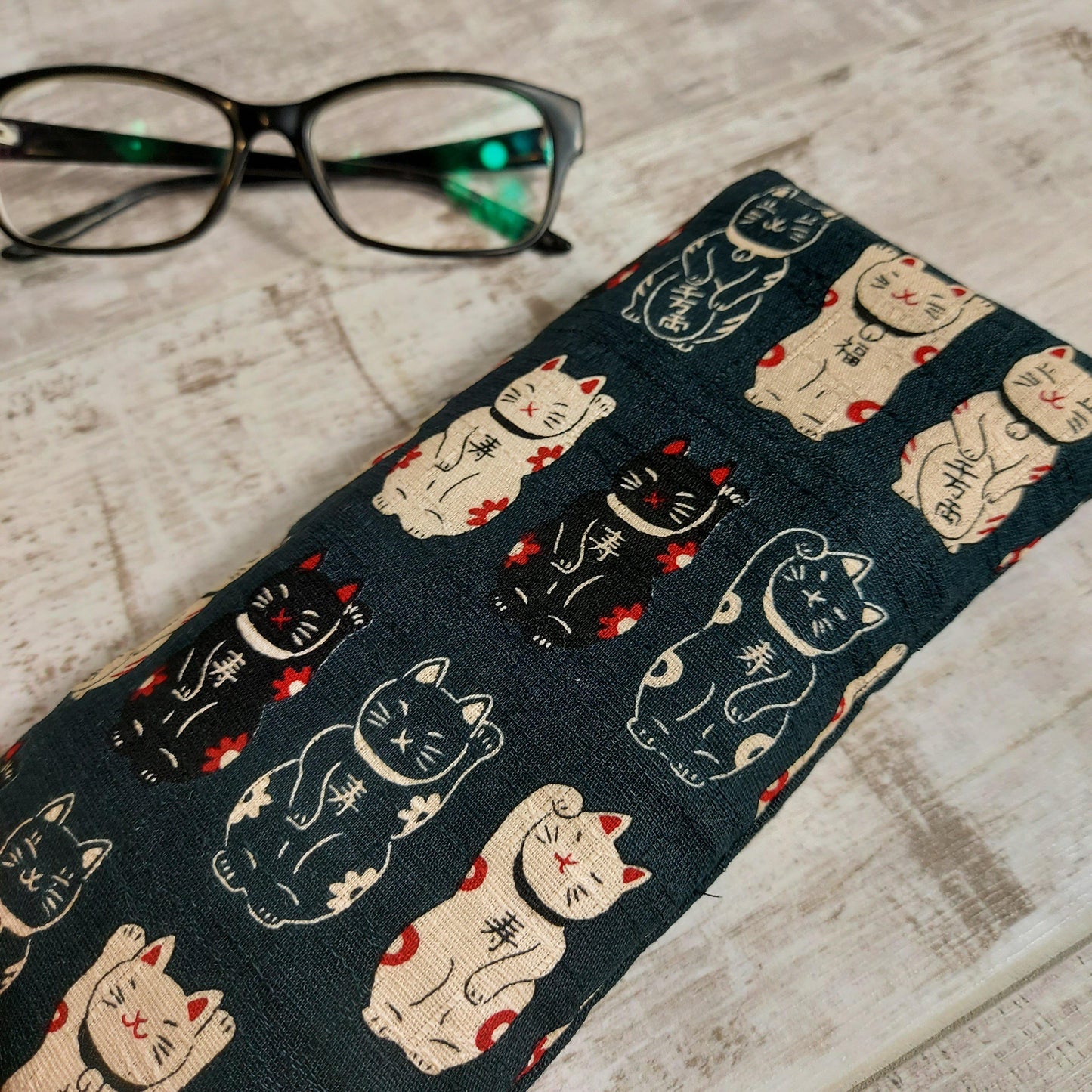 Black lucky cat glasses case by Olganna, pictured with glasses.
