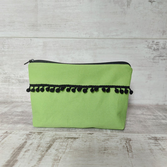 Lime green canvas makeup bag, front view, with black pom poms.
