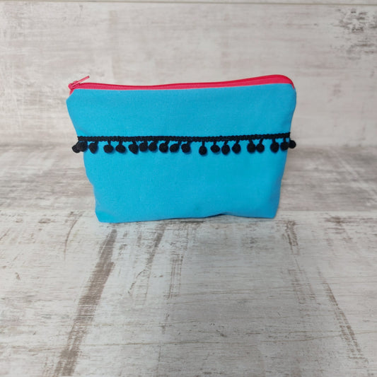 Turquoise canvas makeup bag, front view, with black pom poms.