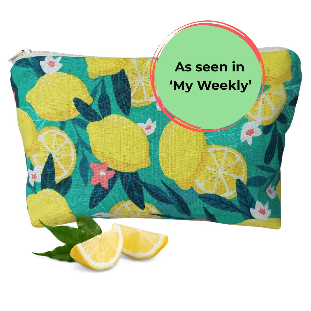 Front view of bold green and yellow Sicilian lemon print makeup bag, pictured with lemon slices and 'As seen in My Weekly' text label.