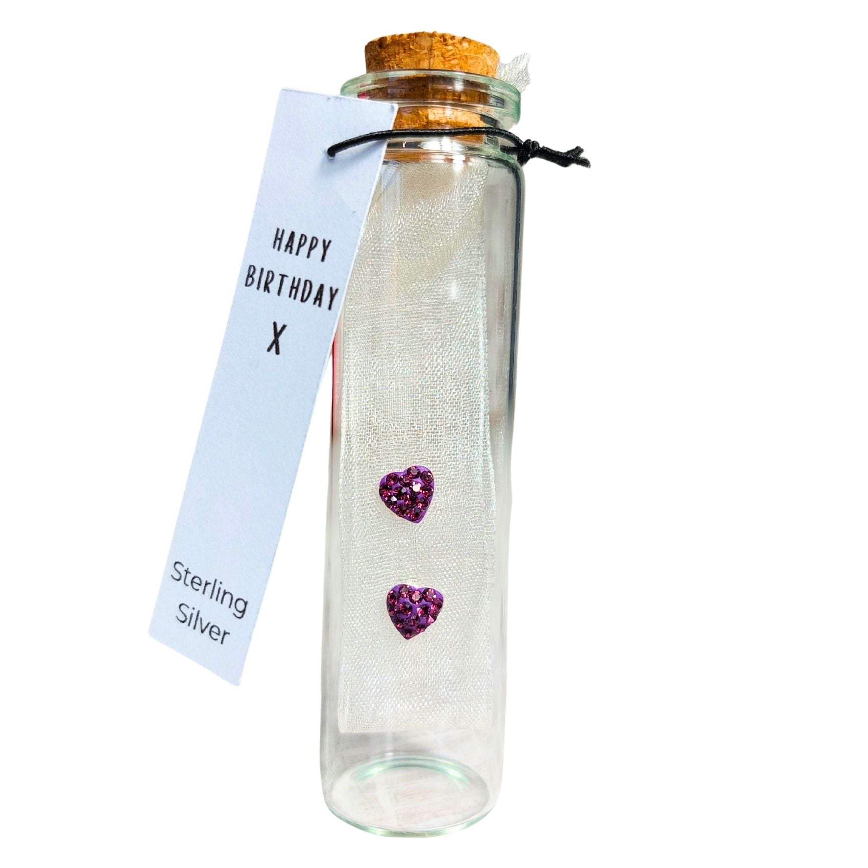 Purple amethyst heart earrings with multiple crystals. Presented on fabric in a glass bottle with cork top. A tag is attached which says 'happy birthday' and the words sterling silver.