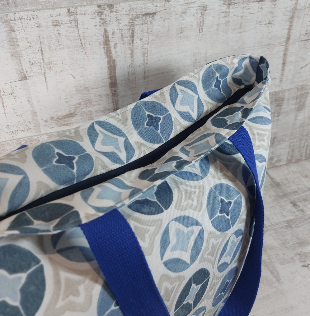 Top view of blue Moroccan tile print beach bag showing deep-set zip closure.