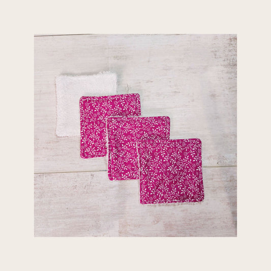 Four bamboo face wipes overlapping, in plum ditsy floral print. 