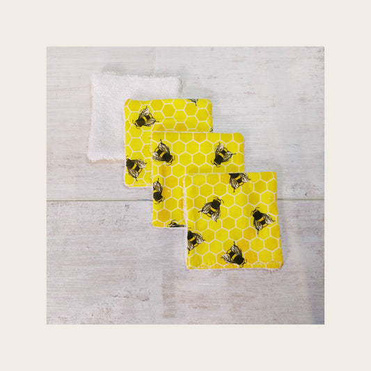 Four bamboo face wipes overlapping, in yellow honeycomb bee print. 