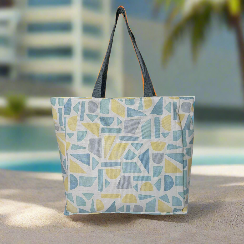 Front view of summery pastel print beach bag on a sunny poolside.