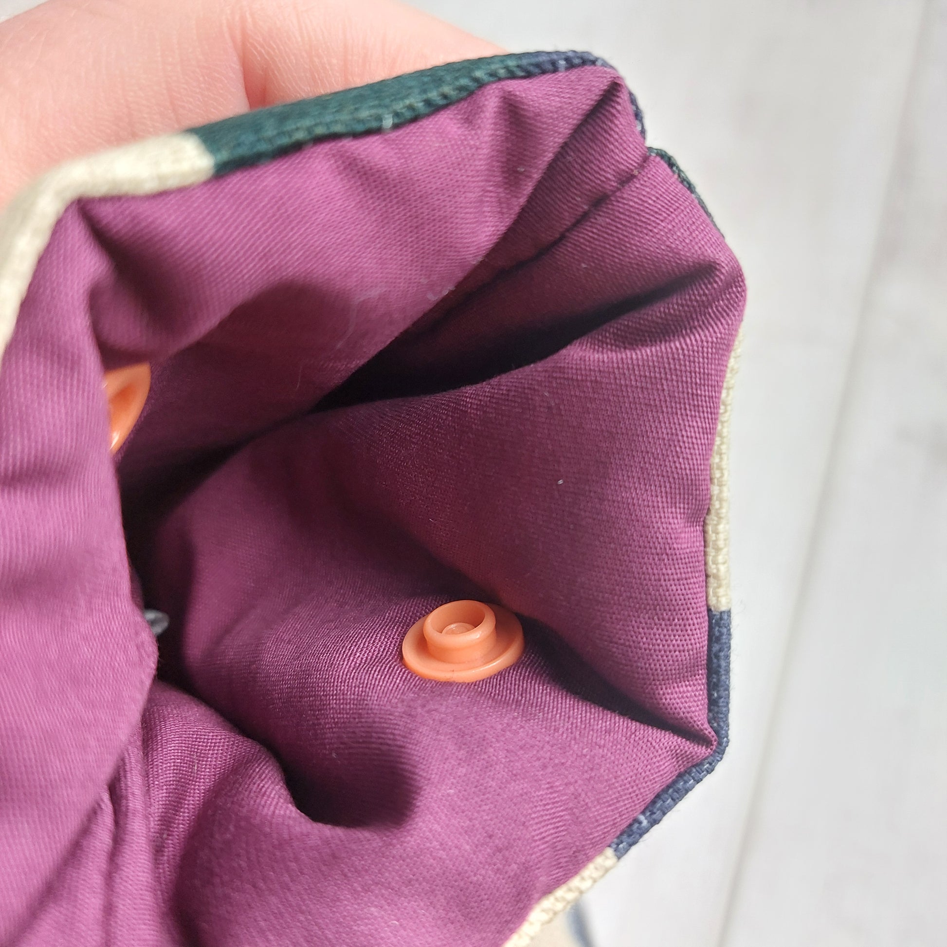 Closeup of a padded glasses case showing a purple lining and snap fastening, by Olganna.