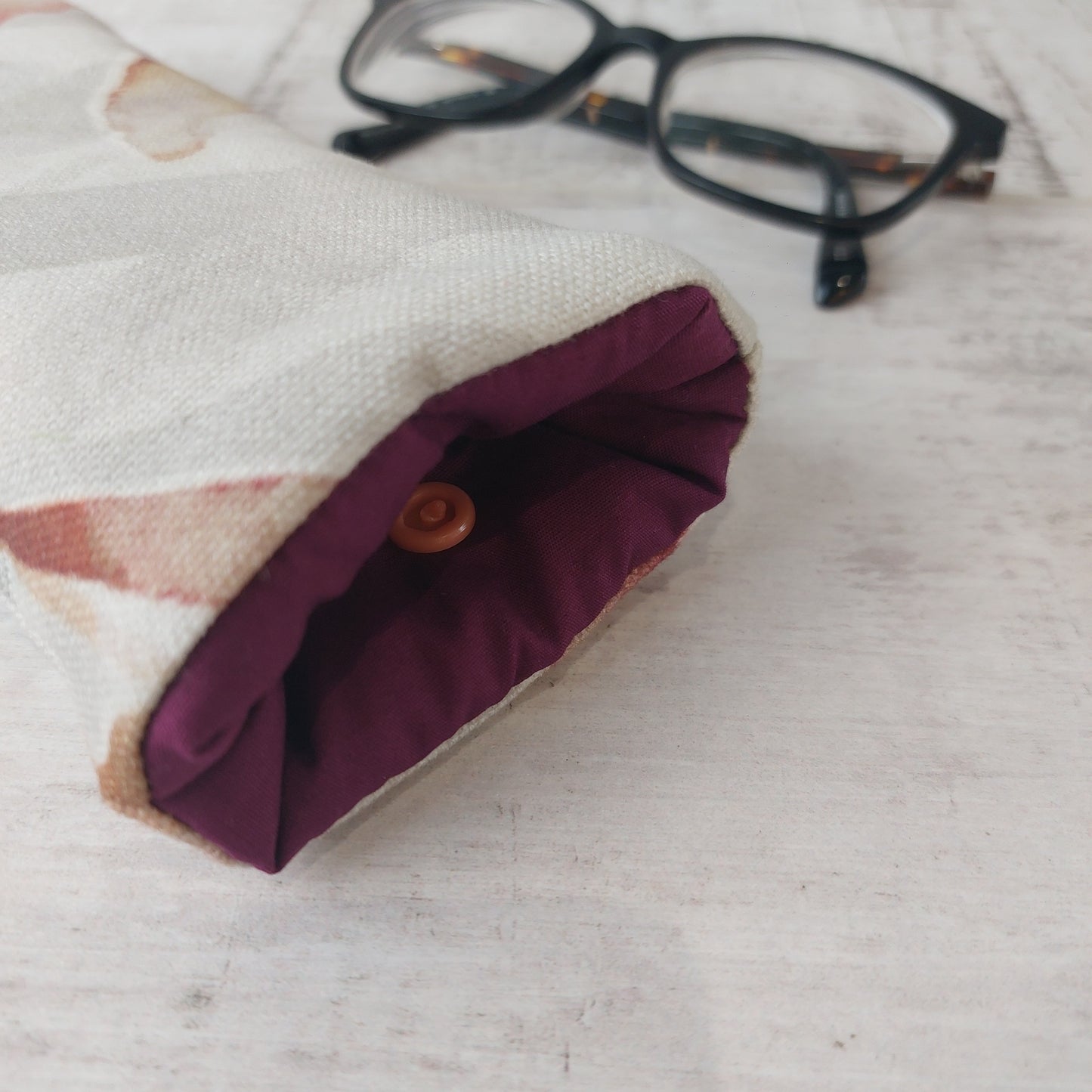 Closeup of Autumn Leaves padded glasses case with plum lining pictured with glasses.