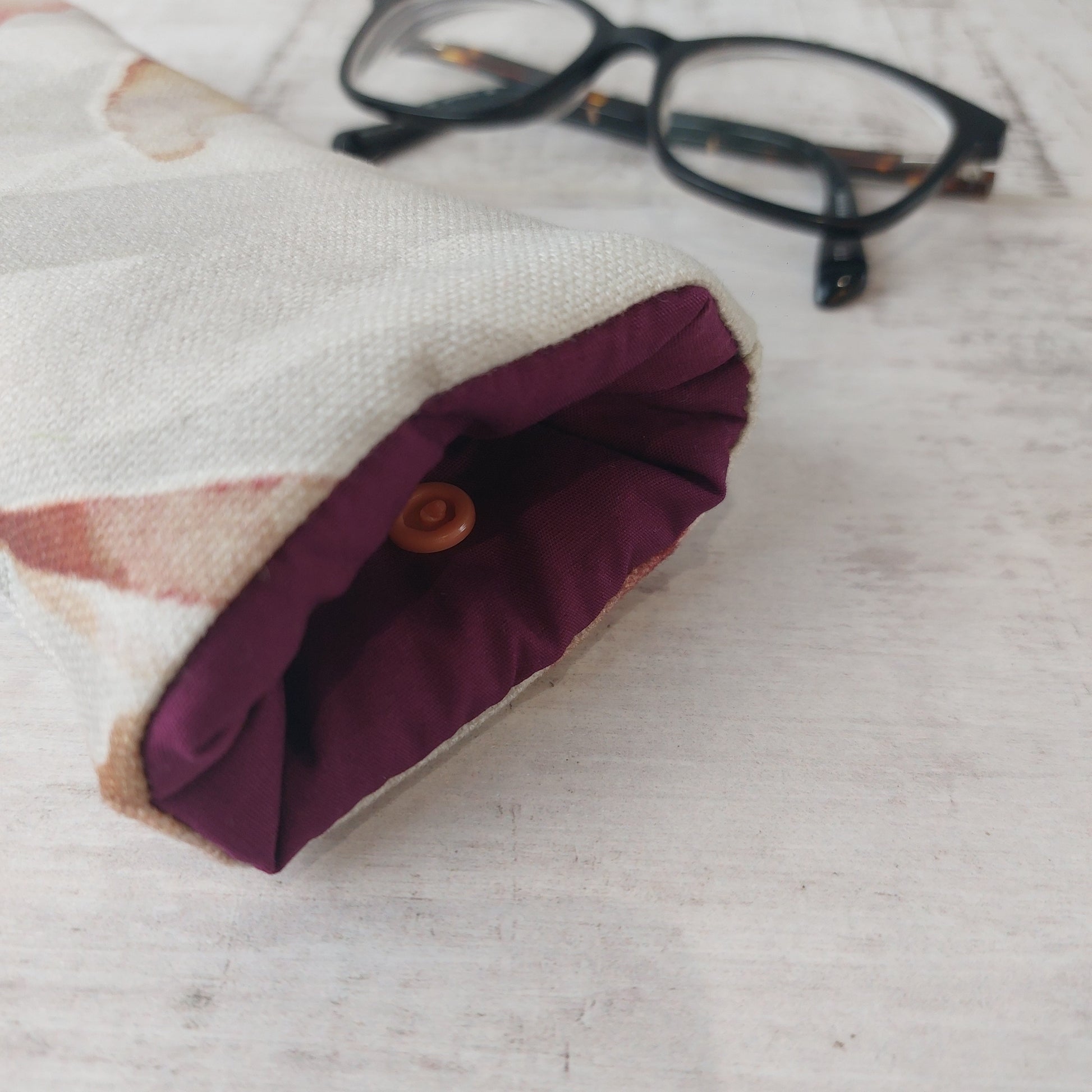 Closeup of Autumn Leaves padded glasses case with plum lining pictured with glasses.