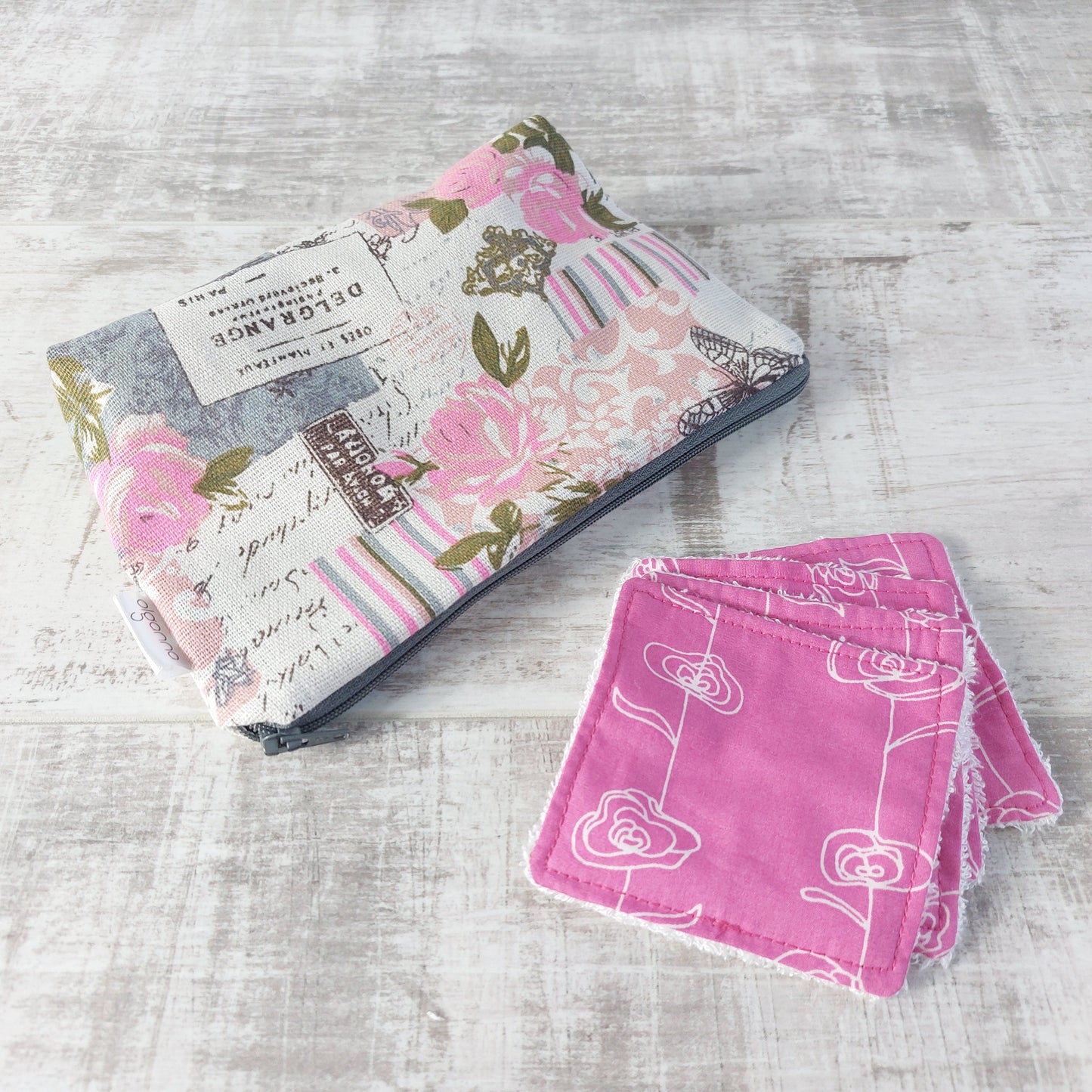 Pink and grey vintage rose and butterfly print makeup bag next to a set of four pink and white rose print reusable face wipes.