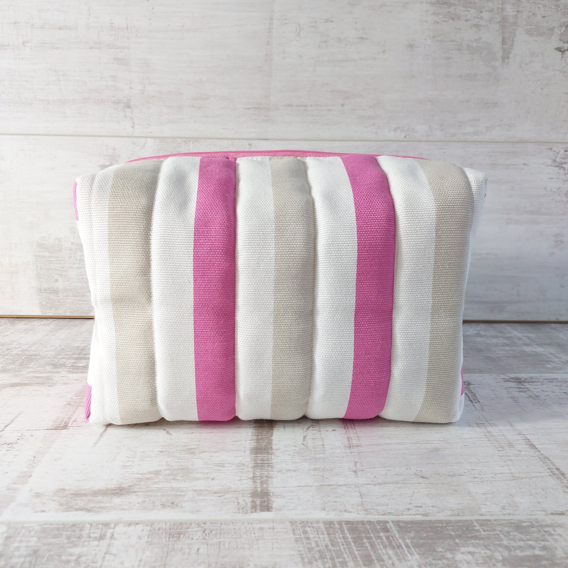 Side view of a quilted boxy bag in nautical style with pink, beige and white stripes and a pink zip, by Olganna.