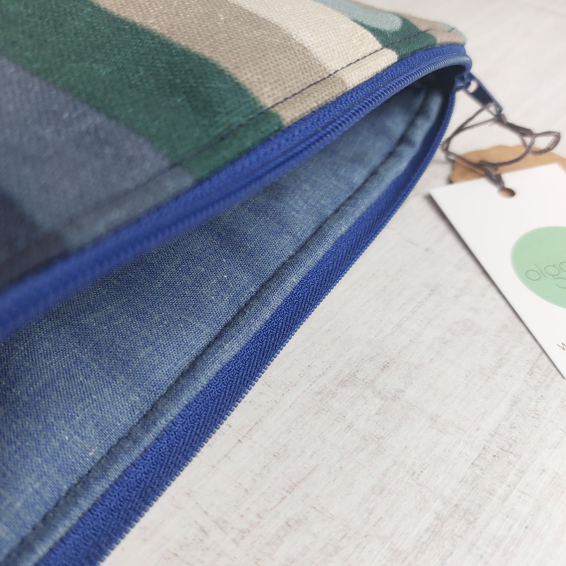 Closeup of toiletries zip bag in blue and winter tones stripe pattern showing blue zip and blue lining.