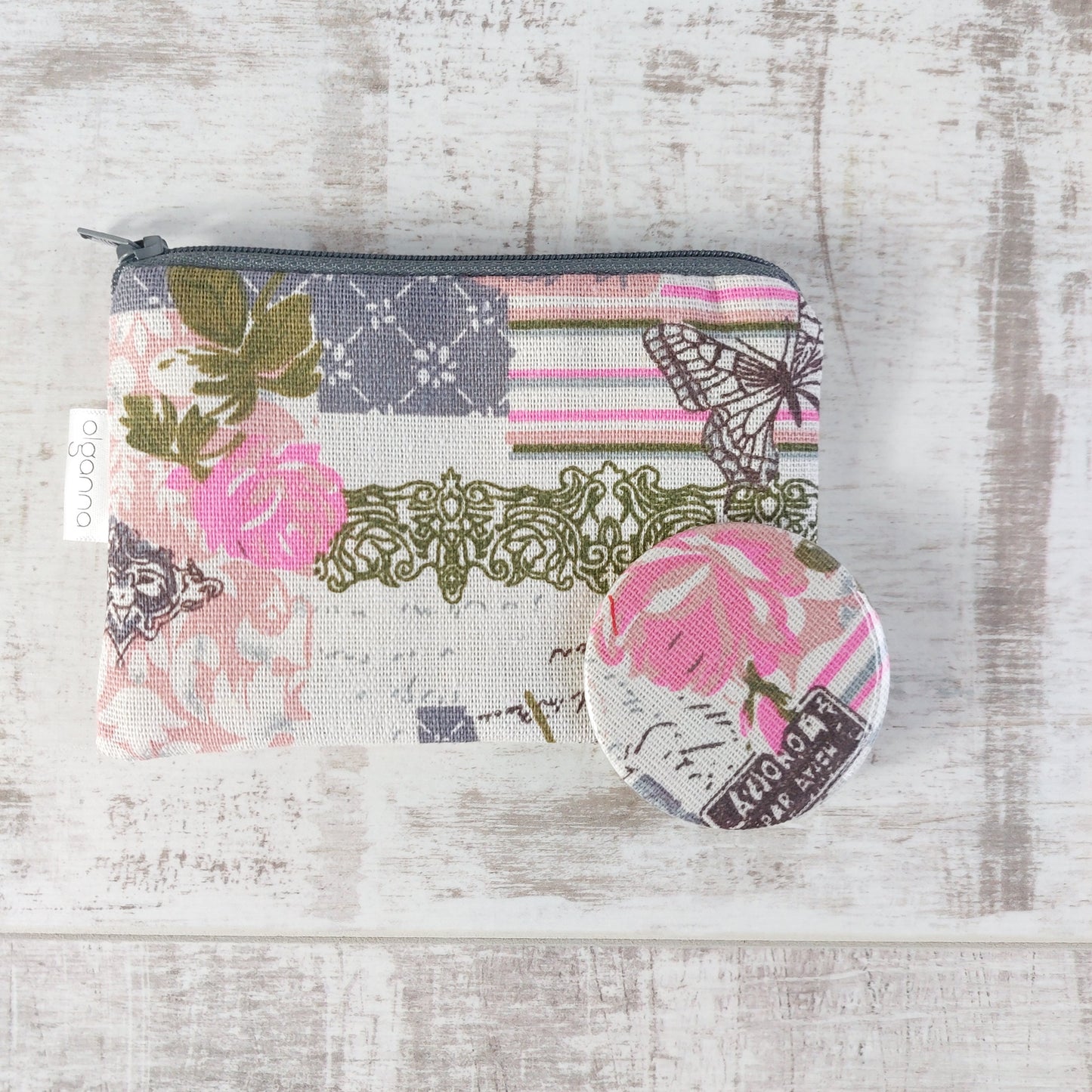 Floral vintage-style print zip purse in a soft pink Paris-inspired design pictured with a matching compact mirror resting on top.