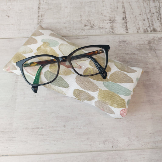 Glasses case in neutral stone pebble print, pictured with glasses.