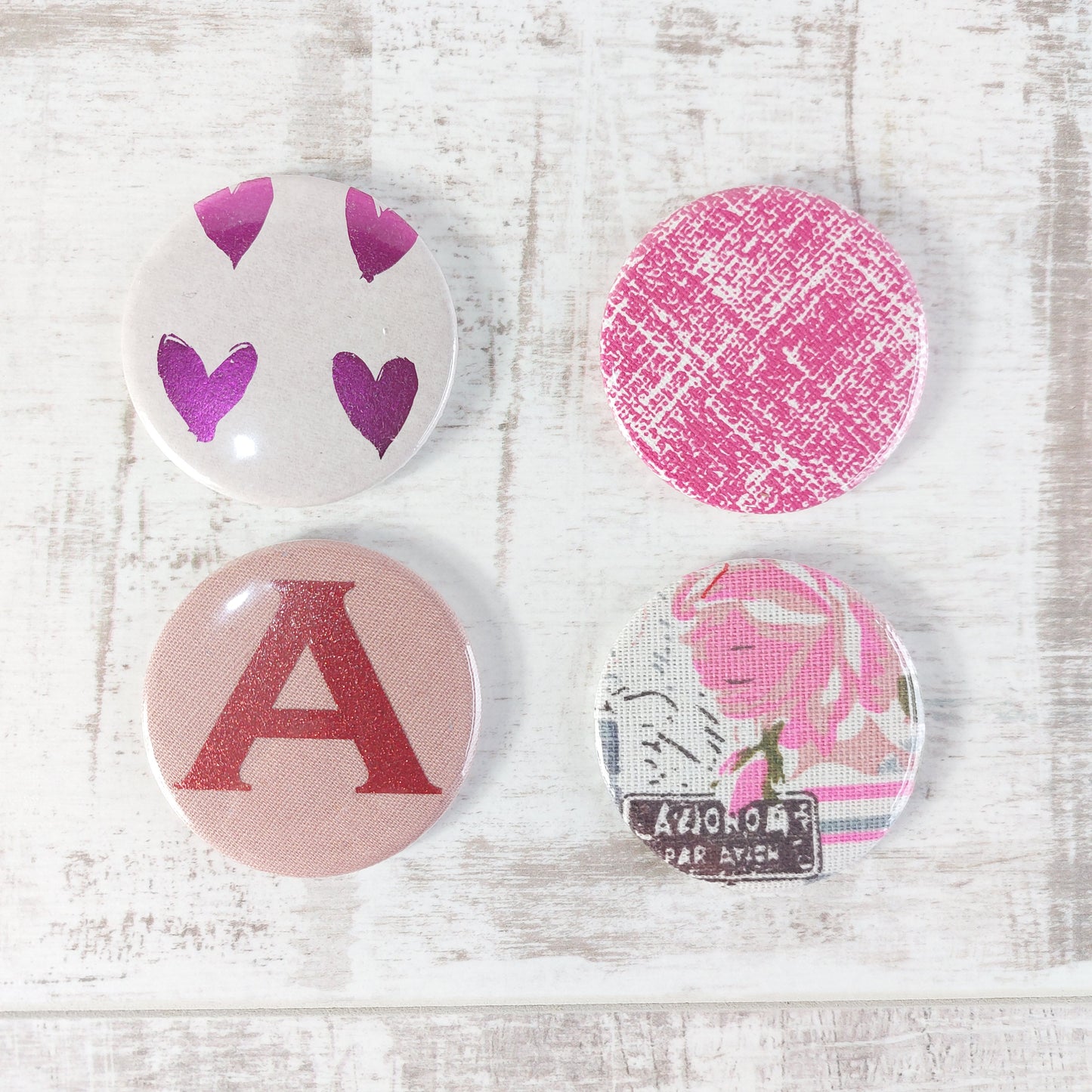 Four compact mirrors in two rows, with different designs featuring pink tones.