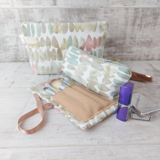 Natural stones print makeup wrap, open to reveal brushes pouch, pictured with matching makeup bag with zip fastening and beauty essentials.