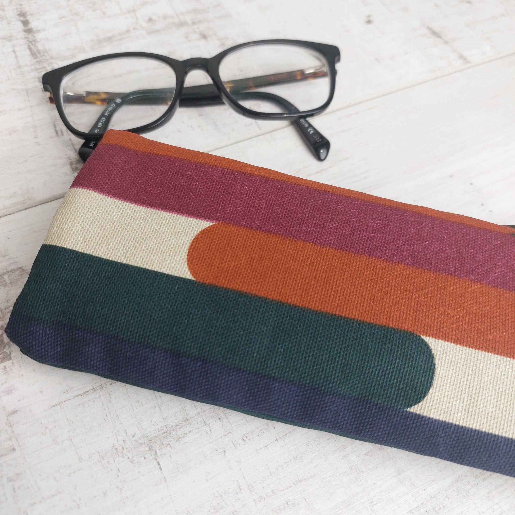 Padded glasses case in autumn tones pictured with glasses.
