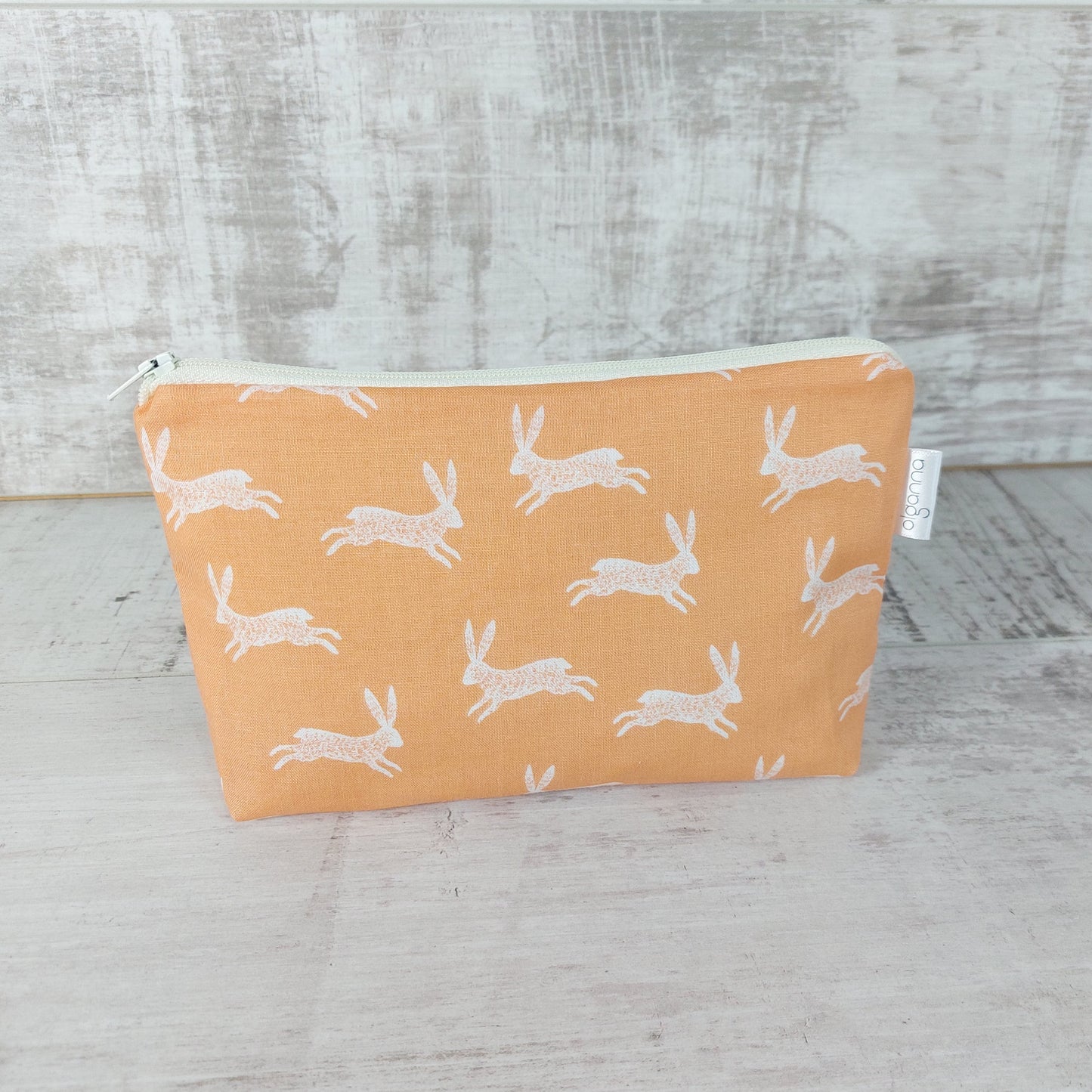 Front view of pale gold bunny print makeup bag. 
