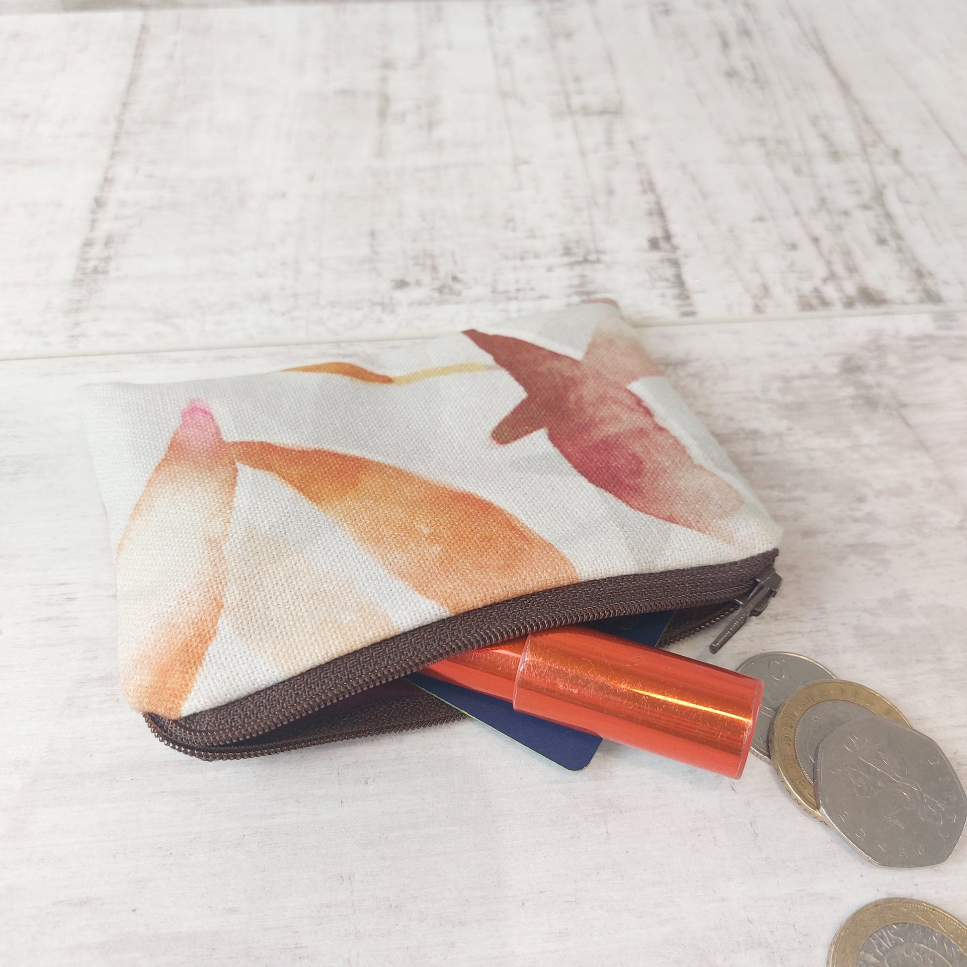 Autumn Leaves zip pouch pictured with coins, card and lipstick.