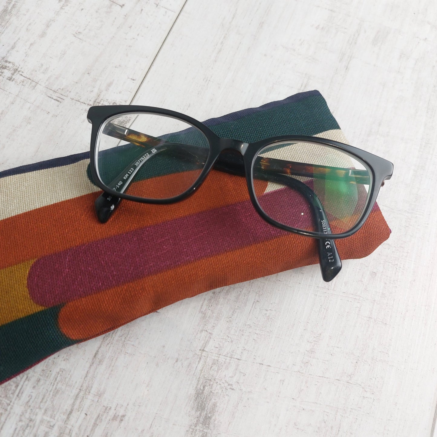 Padded glasses case in autumn tones with glasses resting on top.