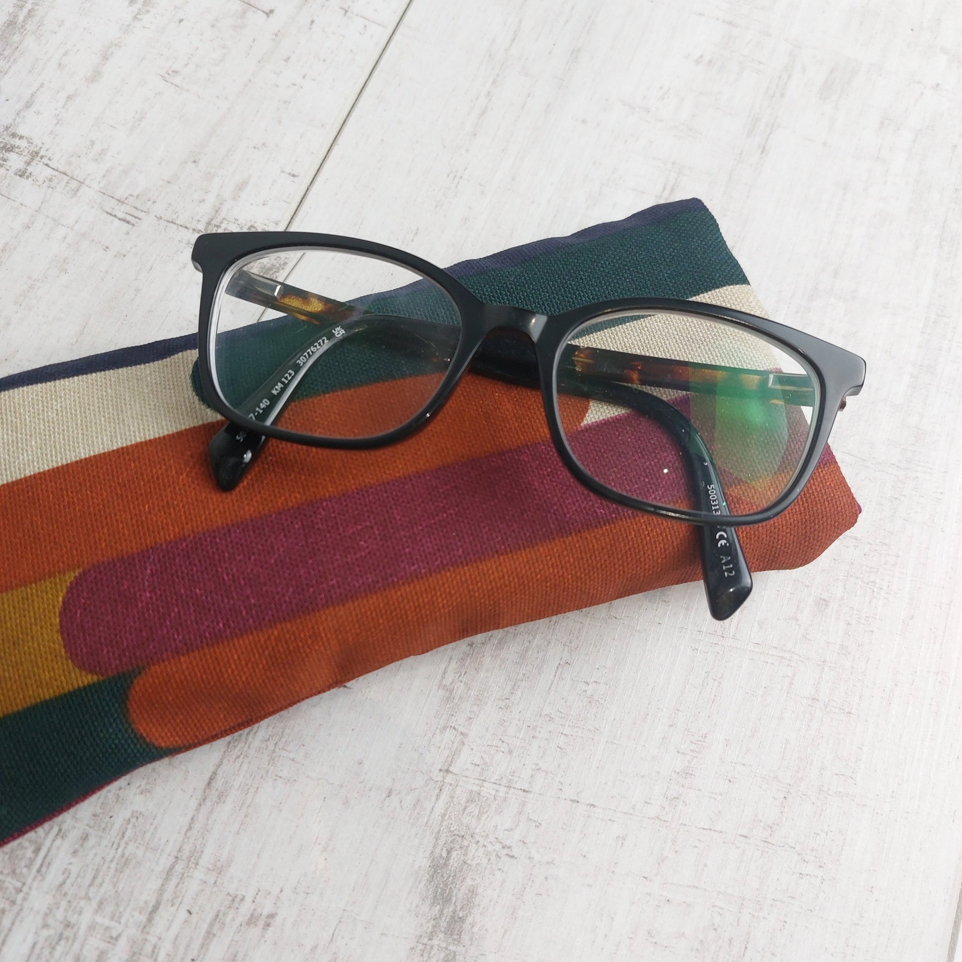 Padded glasses case in autumn tones with glasses resting on top.