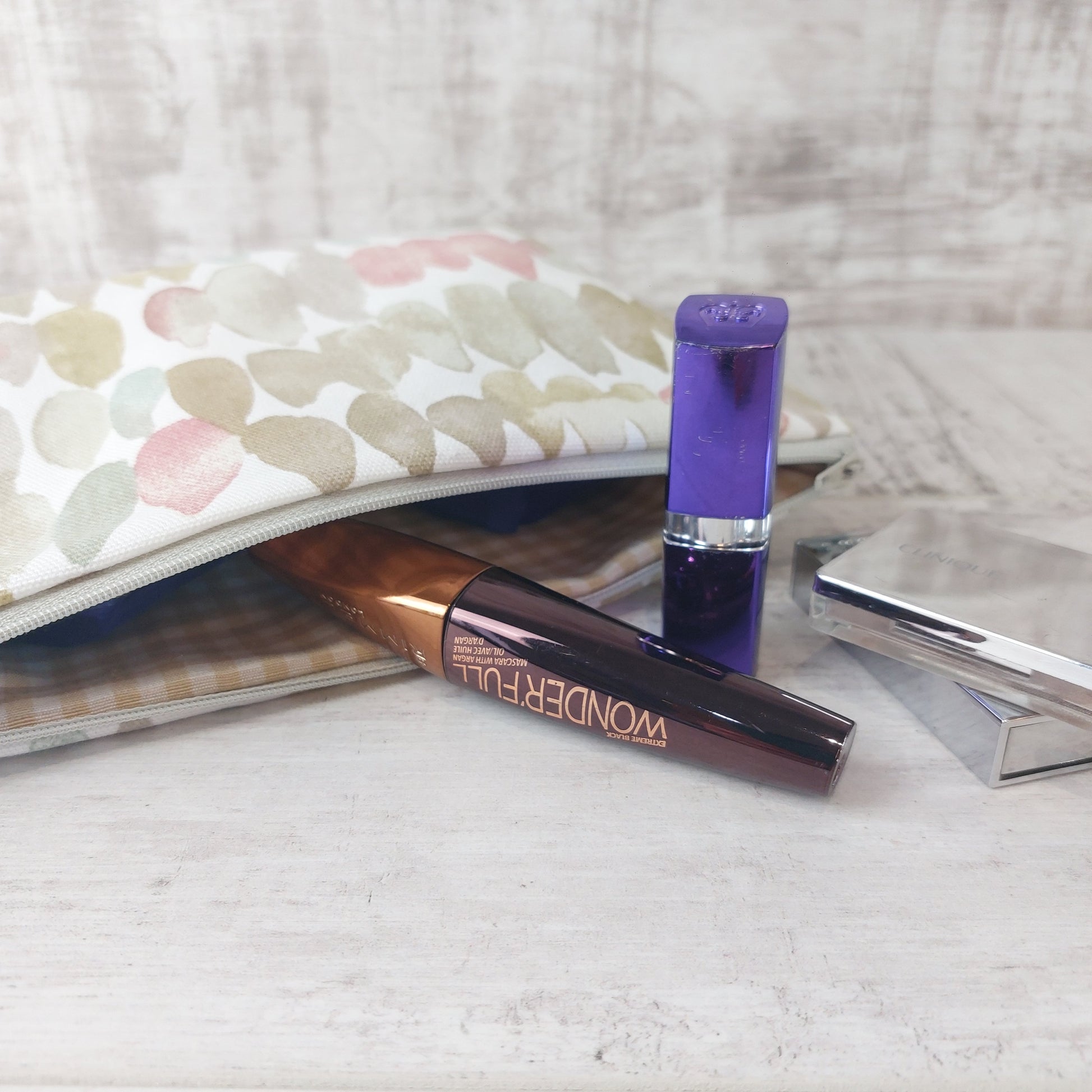 Natural stones print makeup bag, open to reveal gingham lining and pictured with makeup essentials.