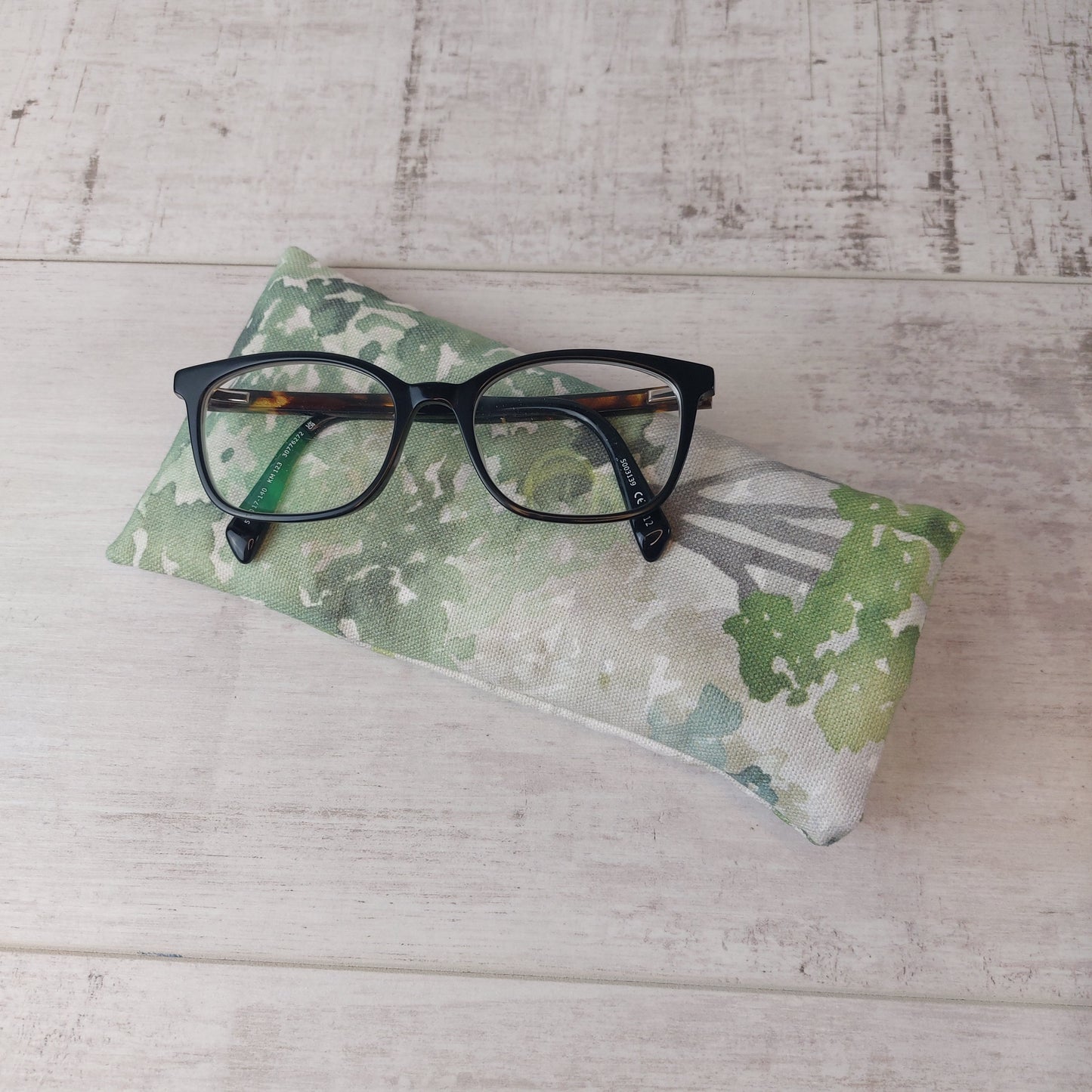 Green watercolour tree print glasses case by Olganna, with glasses on top.