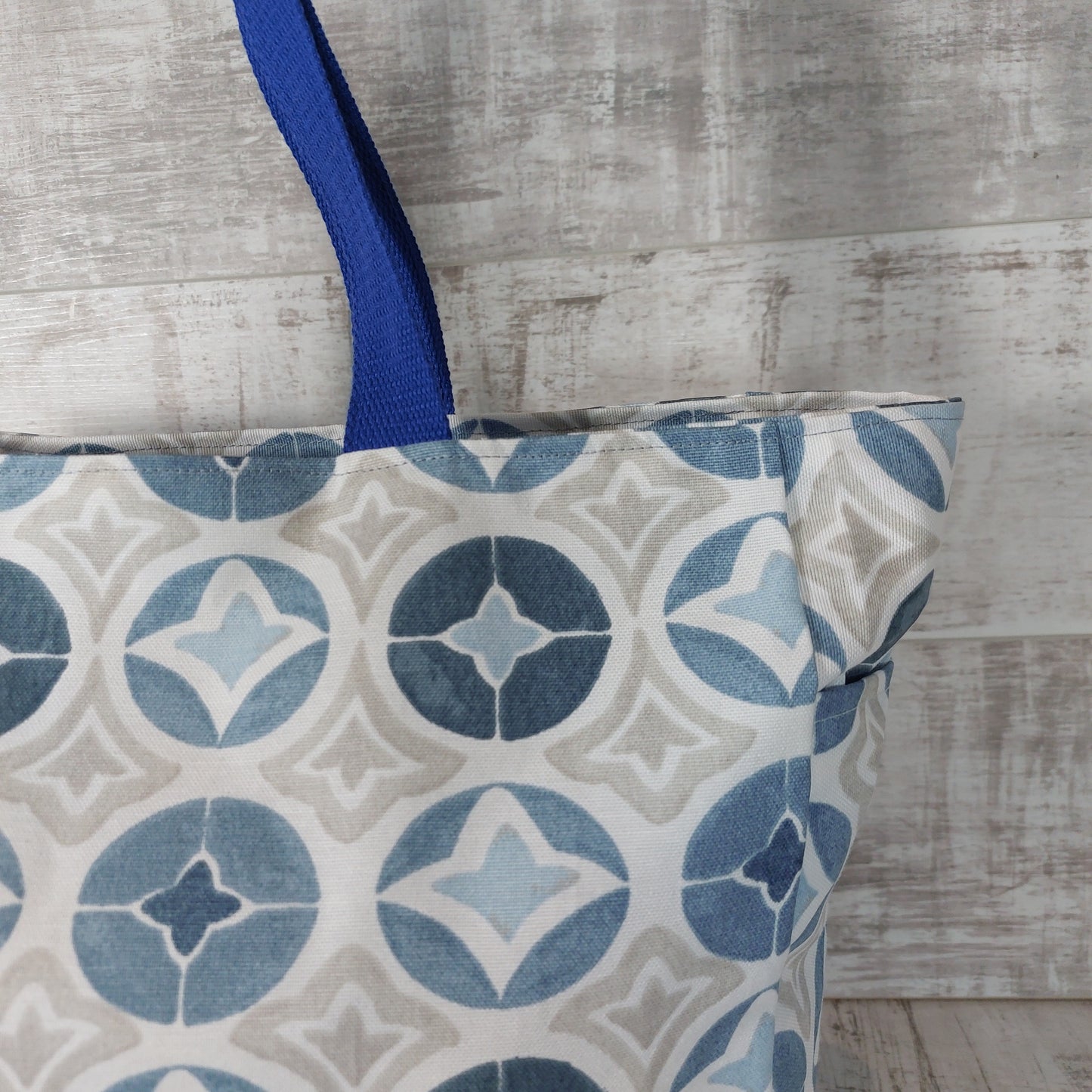 Close-up view of blue Moroccan tile print beach bag showing external pocket.