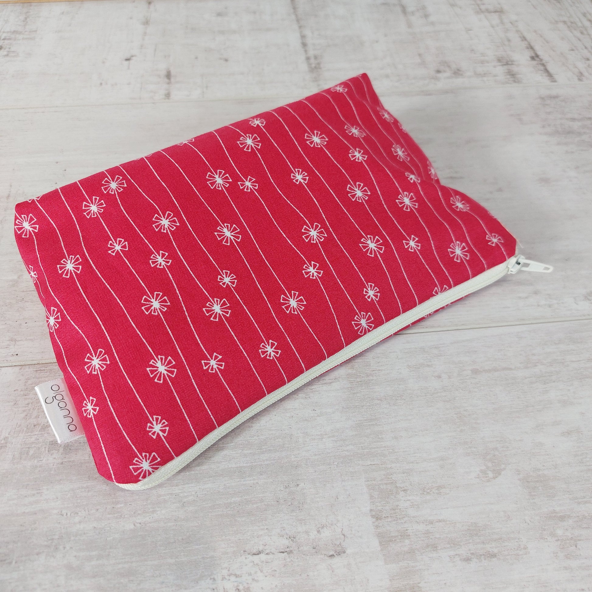Red and white flower print makeup bag, lying down.
