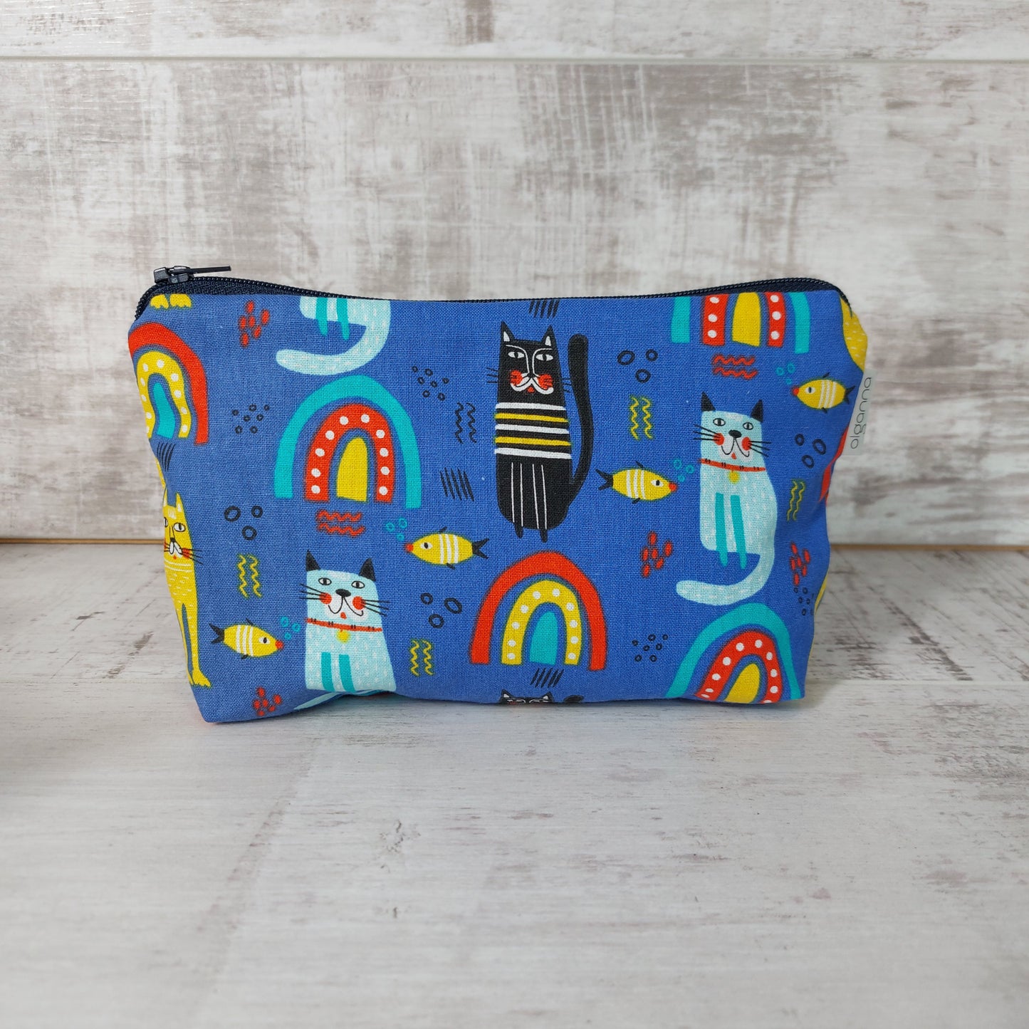 Front view of blue rainbow, cat and fish print makeup bag. 