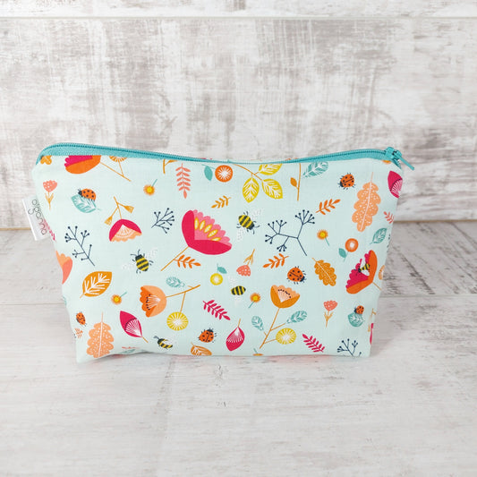 Front view of Spring floral and insect print makeup bag. 